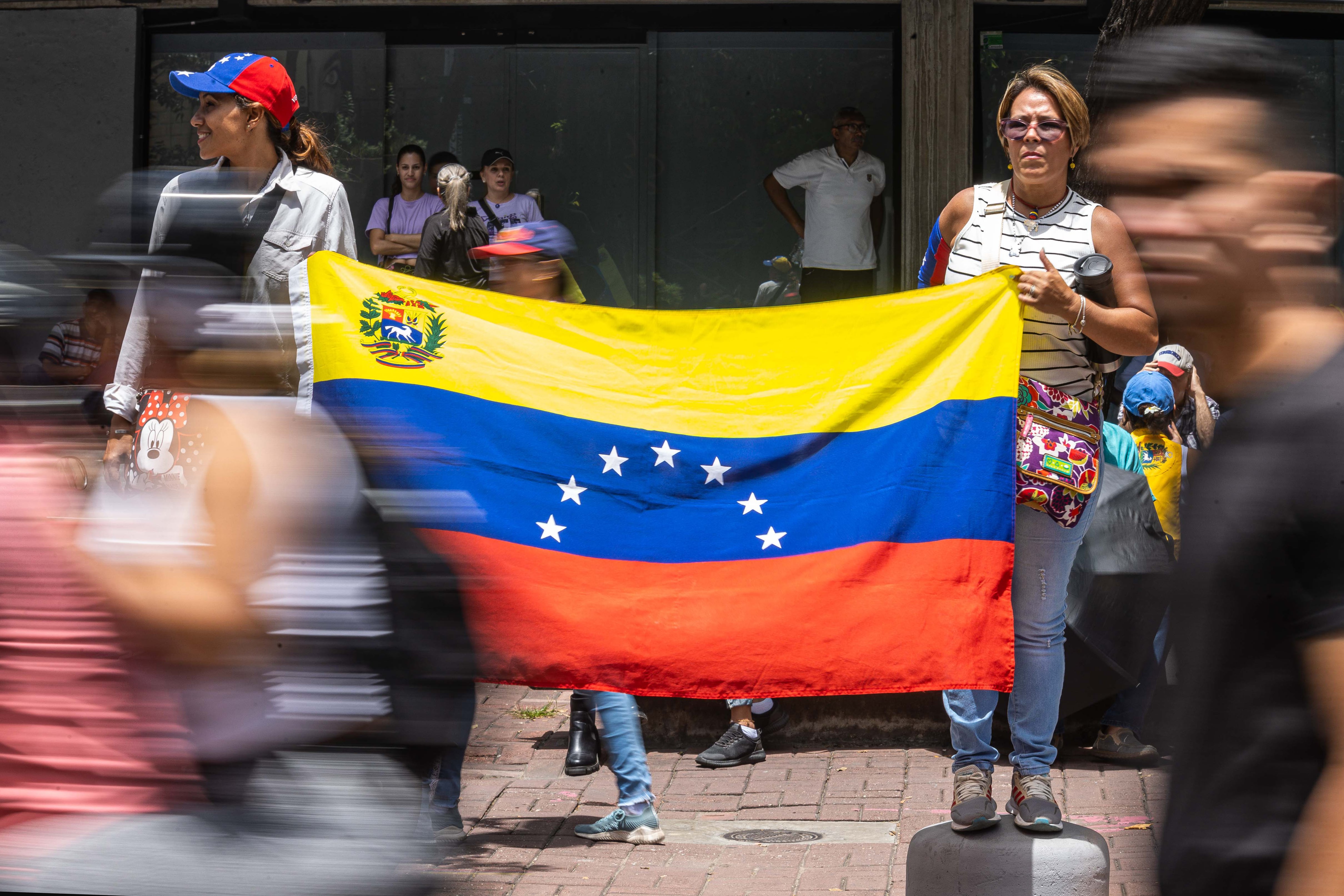 Dos mujeres sostienen una bandera de Venezuela durante una concentración convocada por la líder opositora María Corina Machado y el abanderaro de la oposición, Edmundo González Urrutia, en Caracas (Venezuela). EFE/ Henry Chirinos
