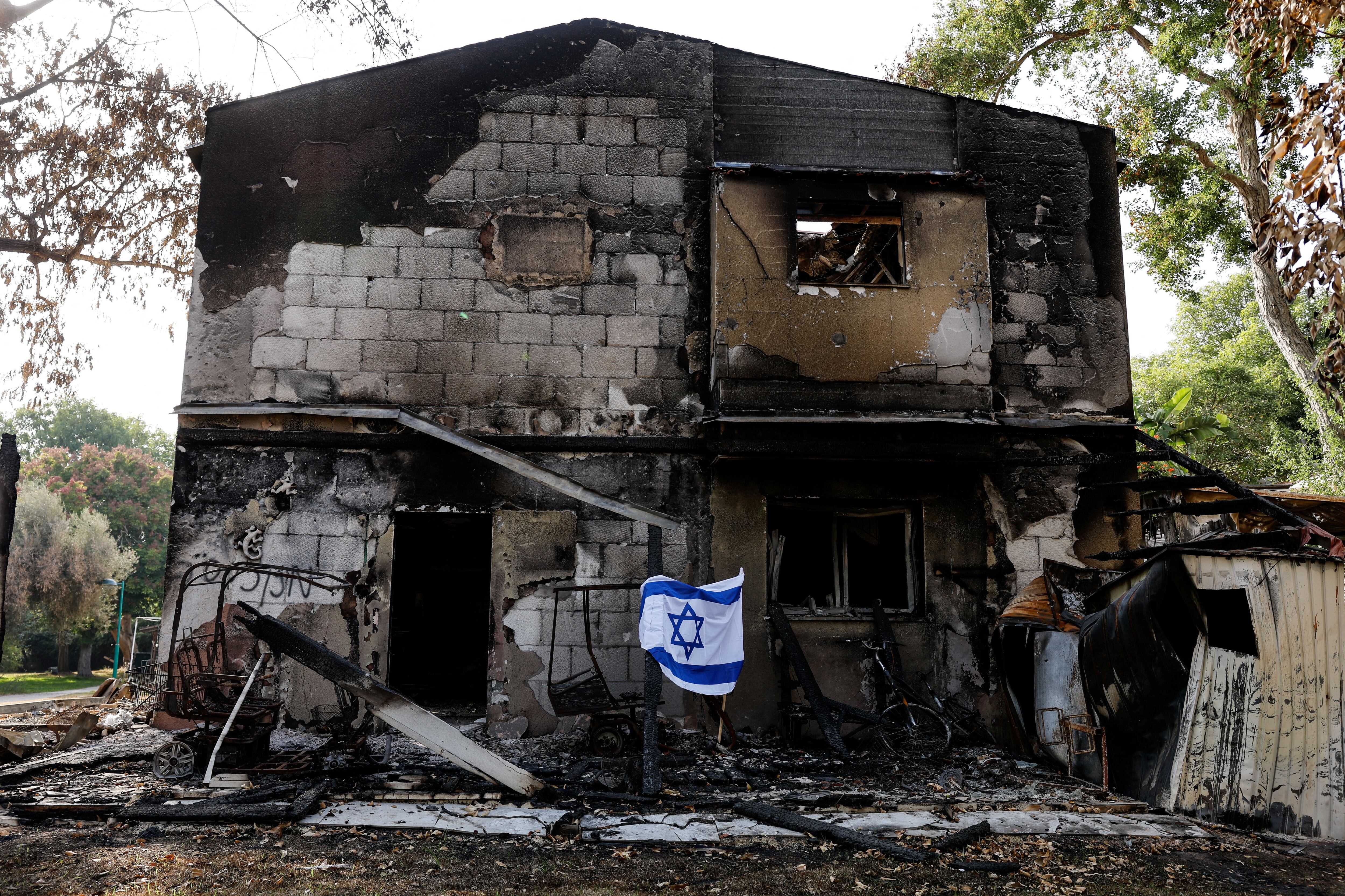 Una bandera israelí ondea frente a los restos de un edificio incendiado tras la infiltración de hombres armados de Hamas en el kibutz Beeri, en el sur de Israel