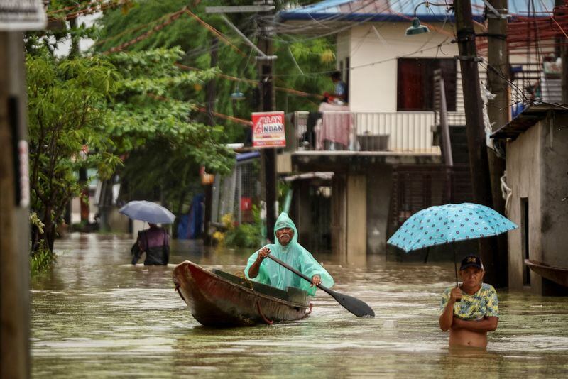 Varias personas vadean las aguas mientras llueve durante la tormenta tropical Yagi, en Filipinas (REUTERS/Eloísa López)