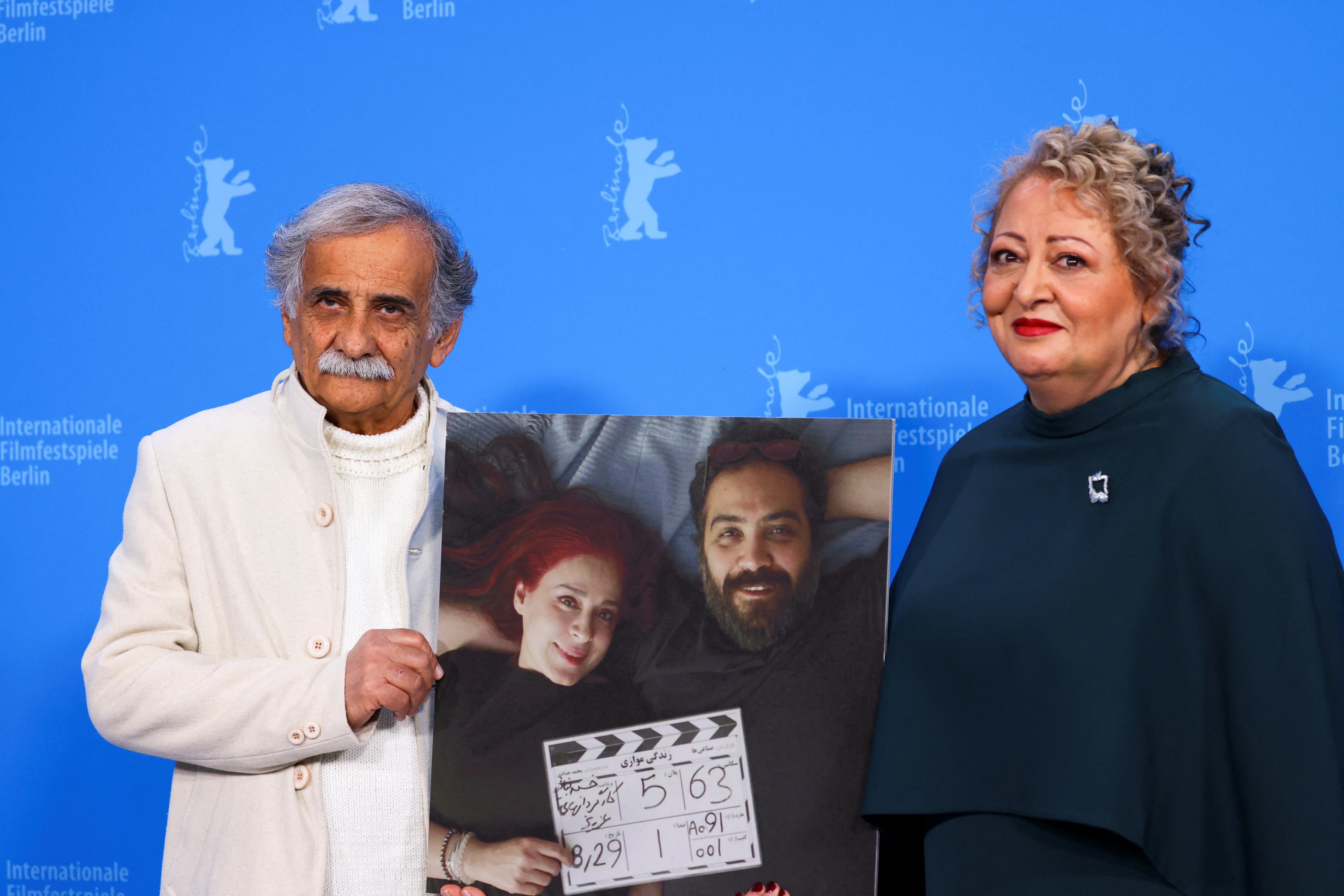 Lily Farhadpour y Esmail Mehrabi sostienen una foto de los directores Maryam Moghaddam y Behtash Sanaeeha mientras asisten a un photocall en la Berlinale (REUTERS/Nadja Wohlleben)