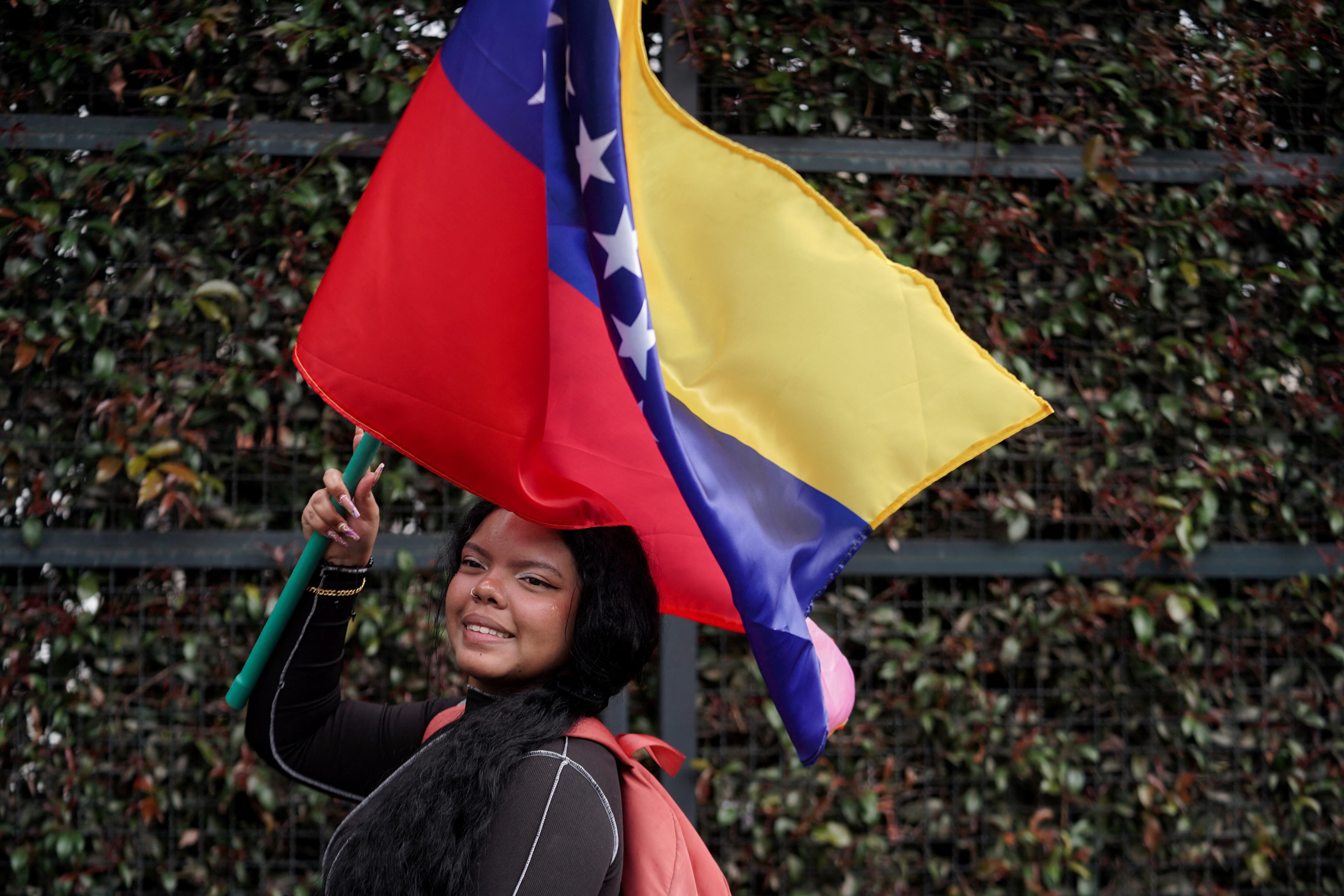 Una mujer venezolana sostiene una bandera venezolana en un puesto de votación en el Colegio Técnico Palermo en Bogotá, Colombia (REUTERS/Nathalia Angarita)