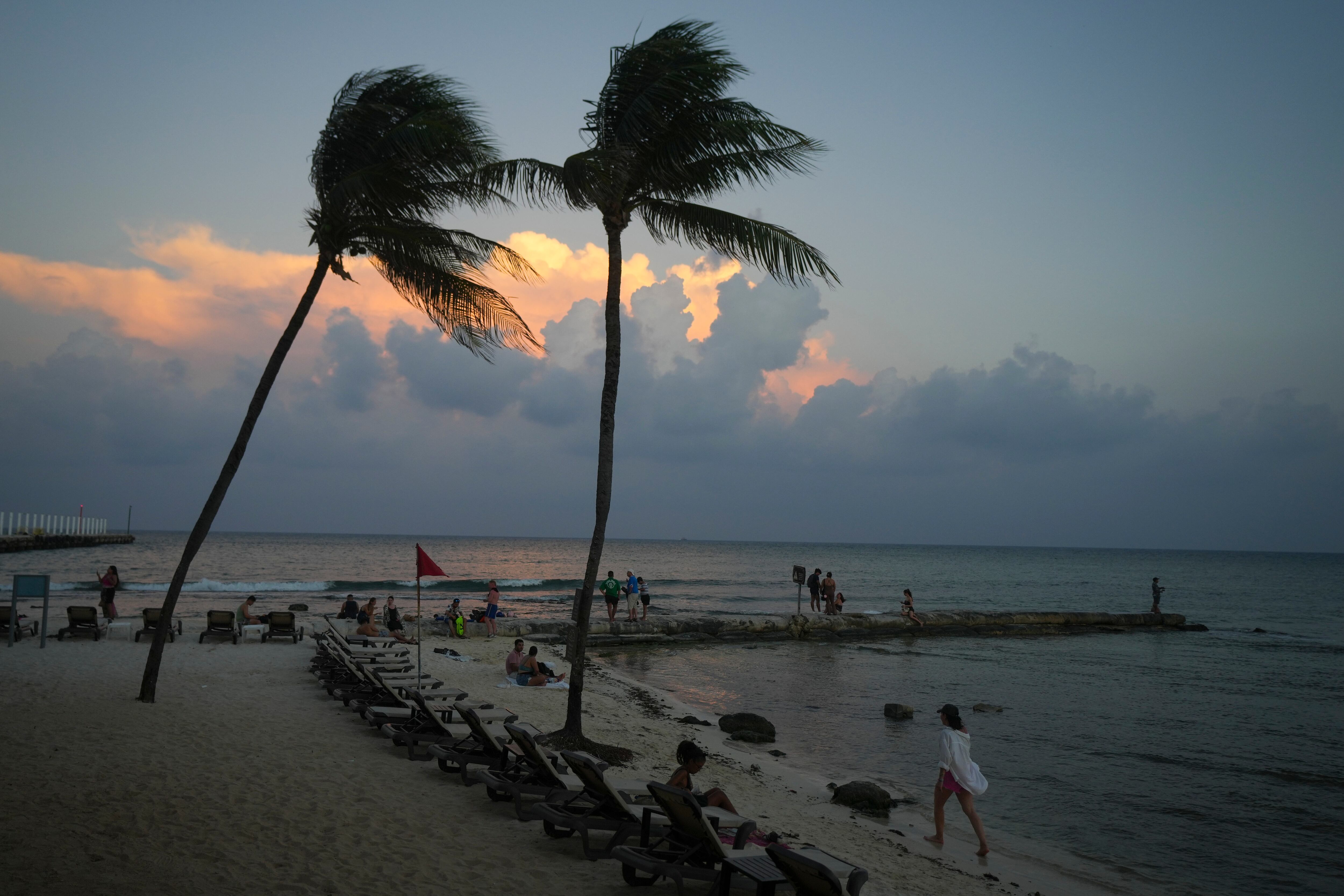 Gente en la playa mientras se pone el sol antes de la llegada del huracán Beryl en Playa del Carmen, México, el miércoles 3 de julio de 2024. (AP Foto/Fernando Llano)