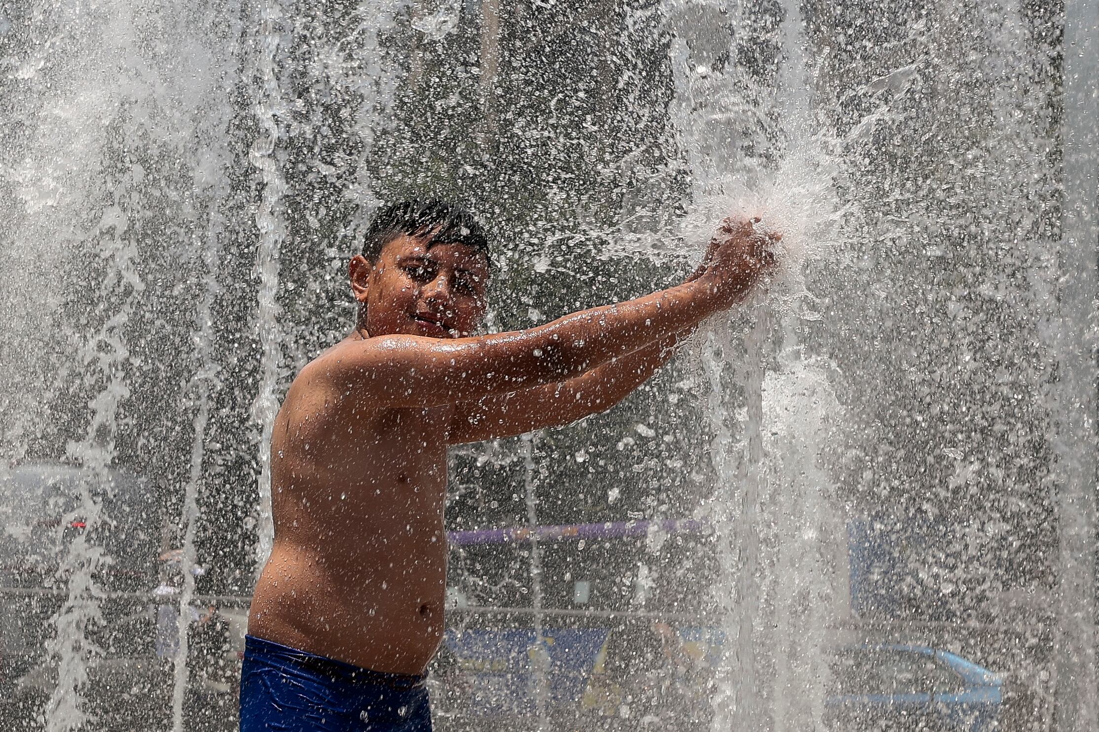 Un niño se baña en una fuente pública, debido a las altas temperaturas registradas en la Ciudad de México (México). EFE/José Méndez
