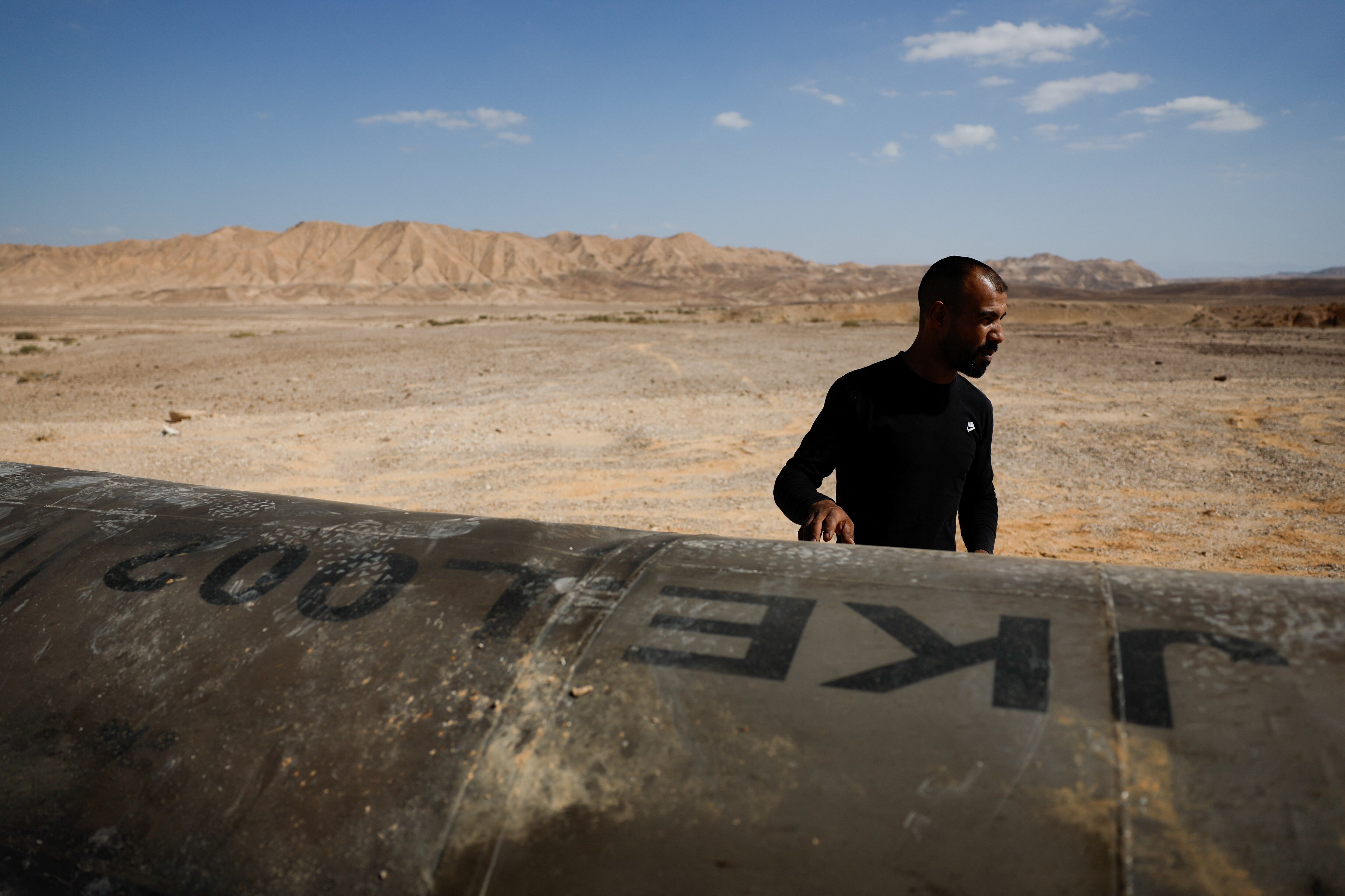 Un hombre se encuentra junto a los aparentes restos de un misil balístico que yacen en el desierto, luego de un ataque de Irán contra Israel, cerca de la ciudad sureña de Arad, Israel