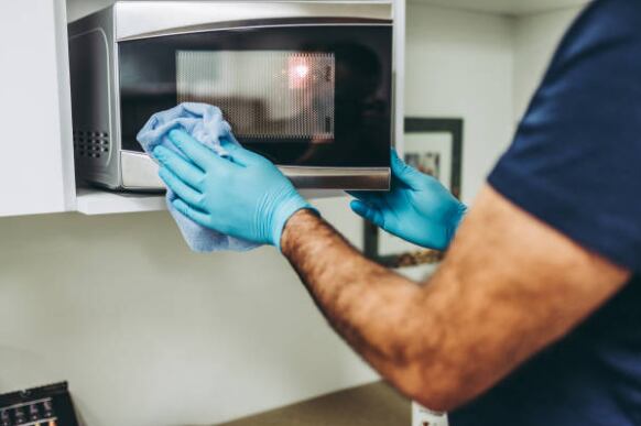 Persona limpiando un microondas, uno de los electrodomésticos que se puede higienizar mediante este método (Getty Images)