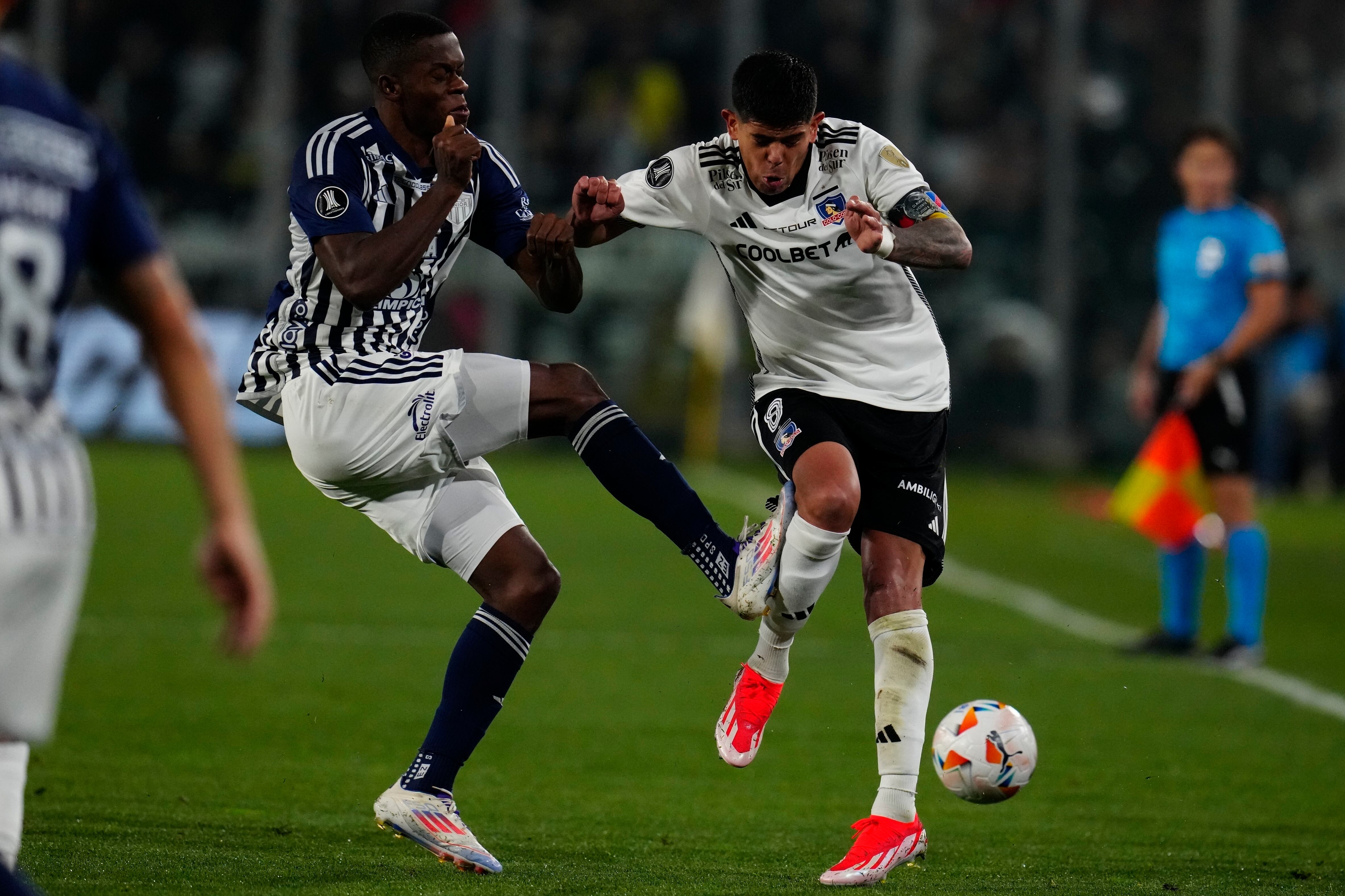 Andrés Colorado, del Junior de Colombia, comete una falta sobre Esteban Pavez, de Colo Colo de Chile, en un partido de la Copa Libertadores en Santiago - crédito Esteban Félix/AP Foto