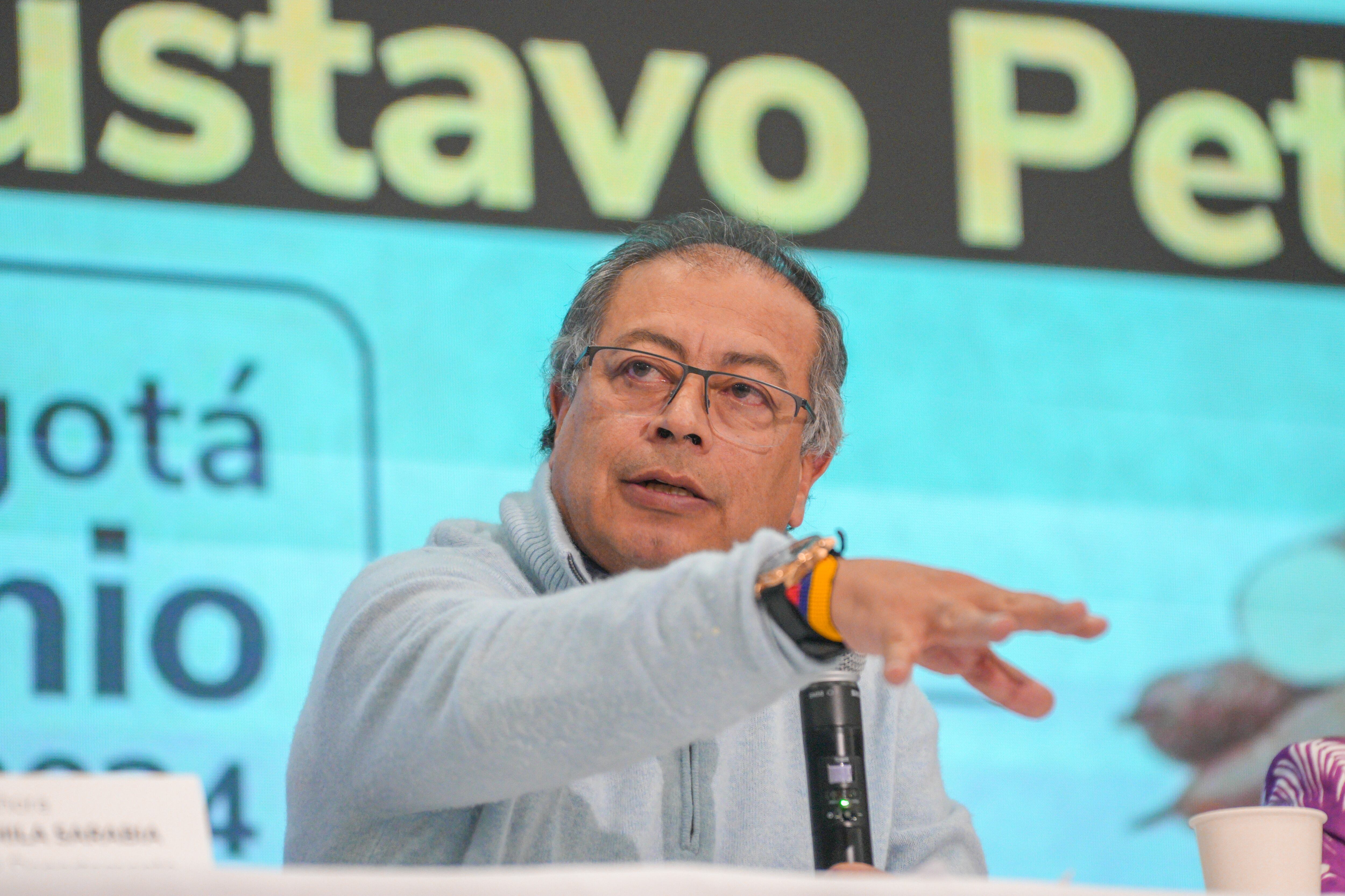 Presidente Gustavo Petro con la mano extendida, hablando, con su nombre grande detrás