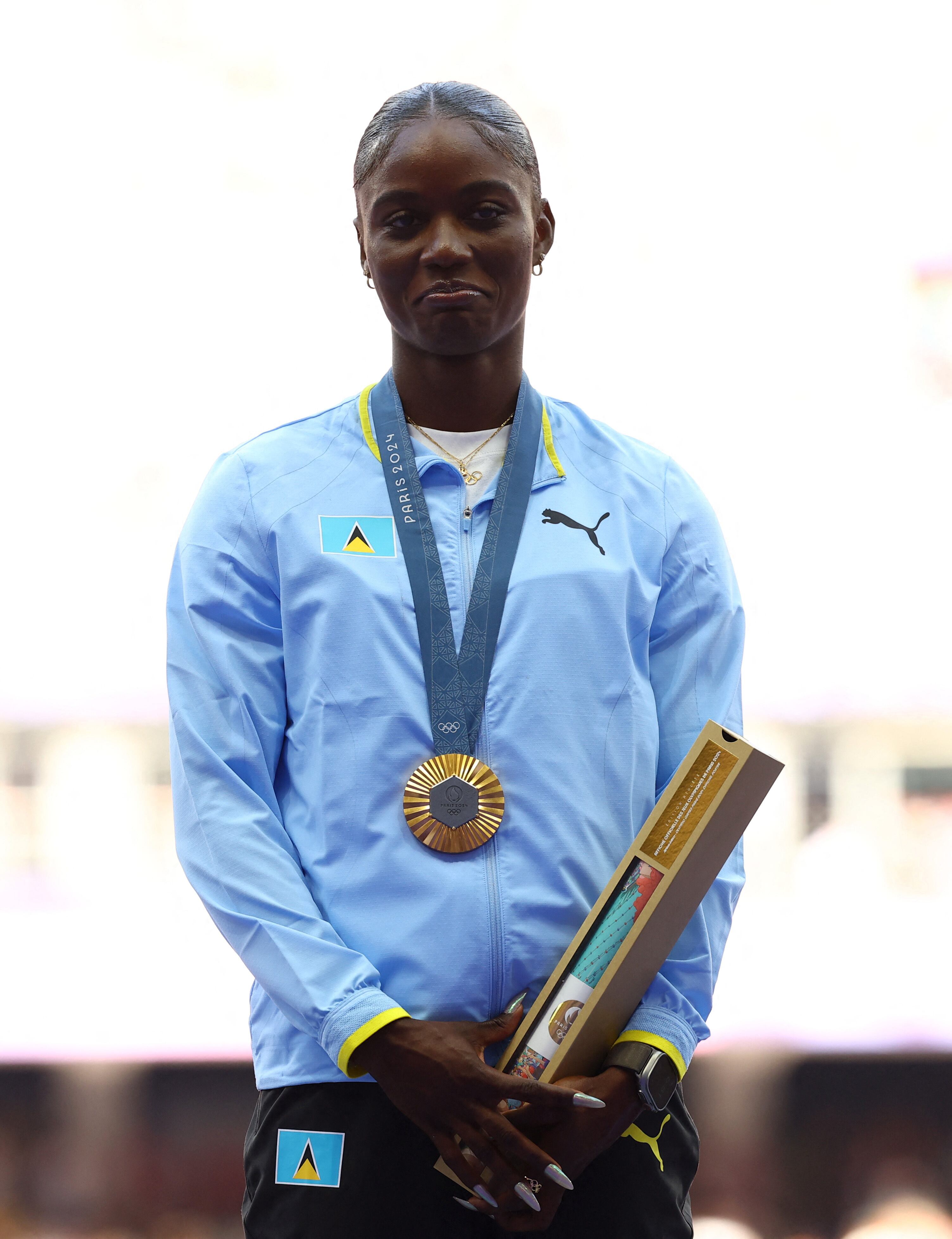 Julien Alfred luce la medalla de oro en lo más alto del podio tras ganar los 100 metros en los Juegos Olímpicos de París 2024 (REUTERS/Kai Pfaffenbach)