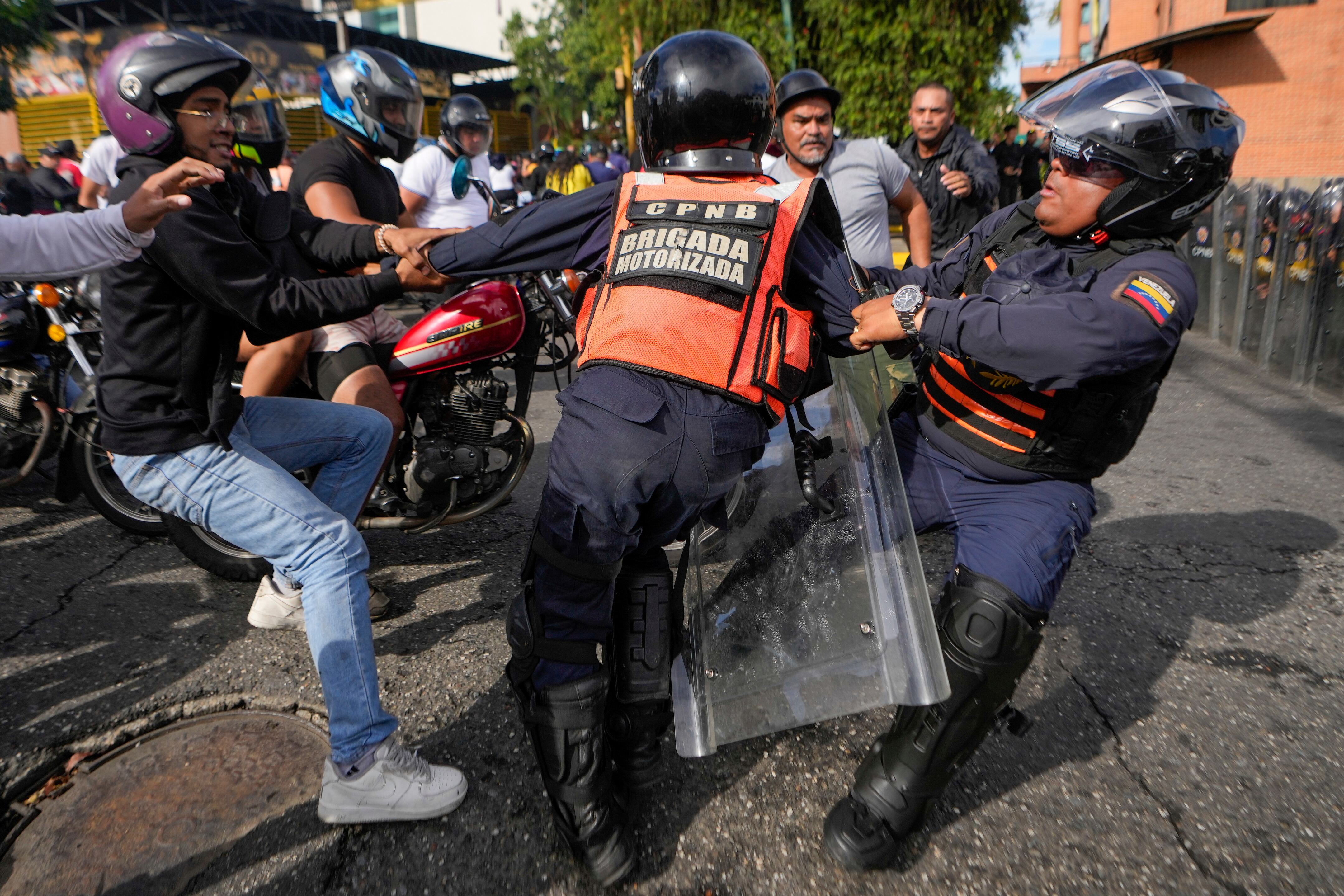 Un manifestante forcejea con la policía en las protestas contra los resultados de las elecciones que dieron por ganador a Nicolás Maduro (AP Foto/Matías Delacroix)