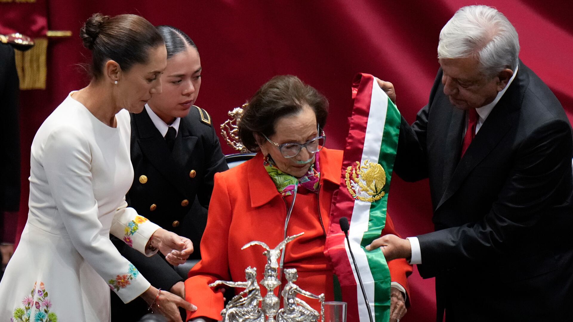 El presidente saliente Andrés Manuel López Obrador entrega la banda presidencial a Ifigenia Martínez, presidenta de la Cámara de Diputados, en la ceremonia de toma de posesión de Claudia Sheinbaum, a la izquierda, en el Congreso en Ciudad de México, el martes 1 de octubre de 2024. (AP Foto/Eduardo Verdugo)