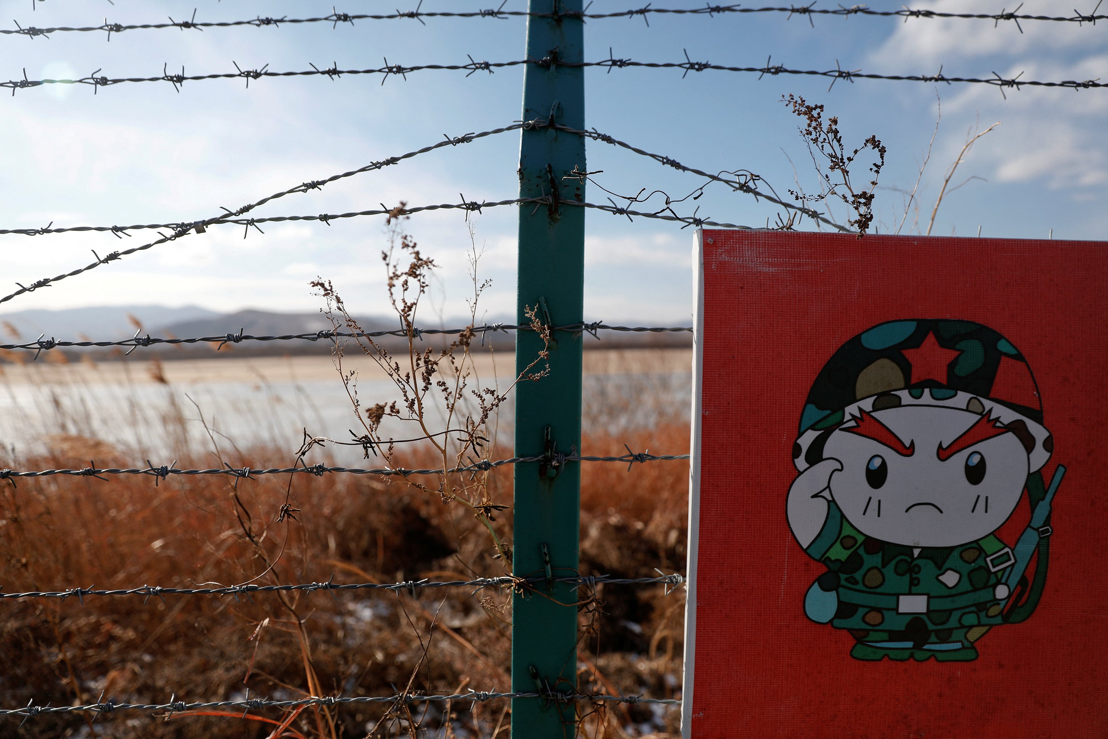 FOTO DE ARCHIVO: Un soldado de caricatura aparece en parte de una señal de advertencia en alambre de púas en el lado chino de la frontera entre Rusia, China y Corea del Norte, cerca de la ciudad de Hunchun, China  (REUTERS/Damir Sagolj/Archivo )