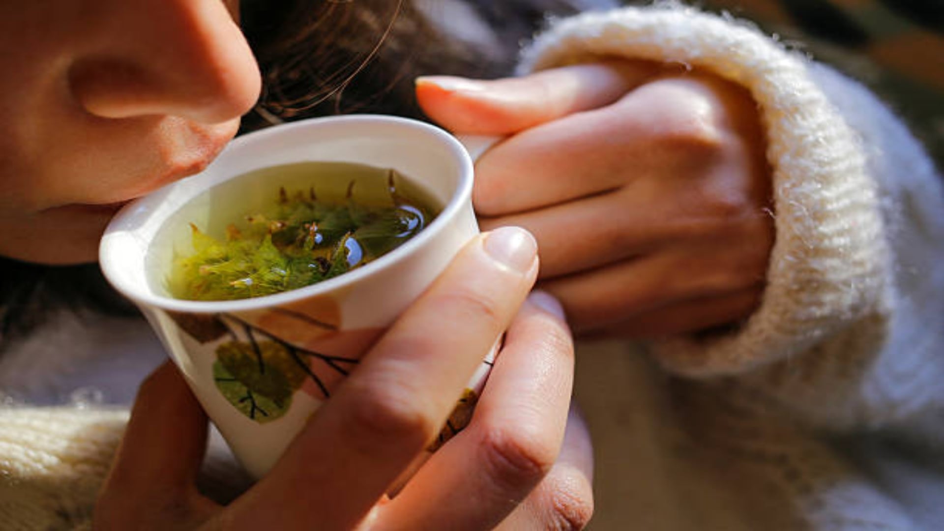 A young woman on the couch and with sage tea on the hand