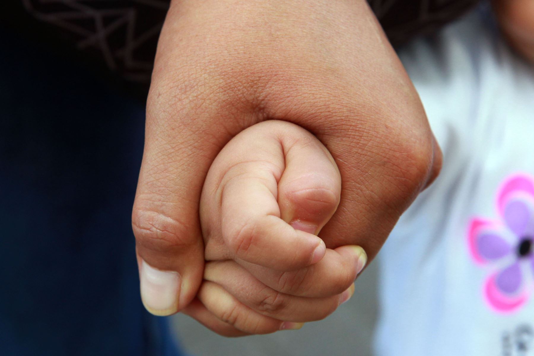 Primer plano de la mano de un hombre adulto cogiendo la mano de una niña pequeña - Abuso sexual infantil (Idehpucp)