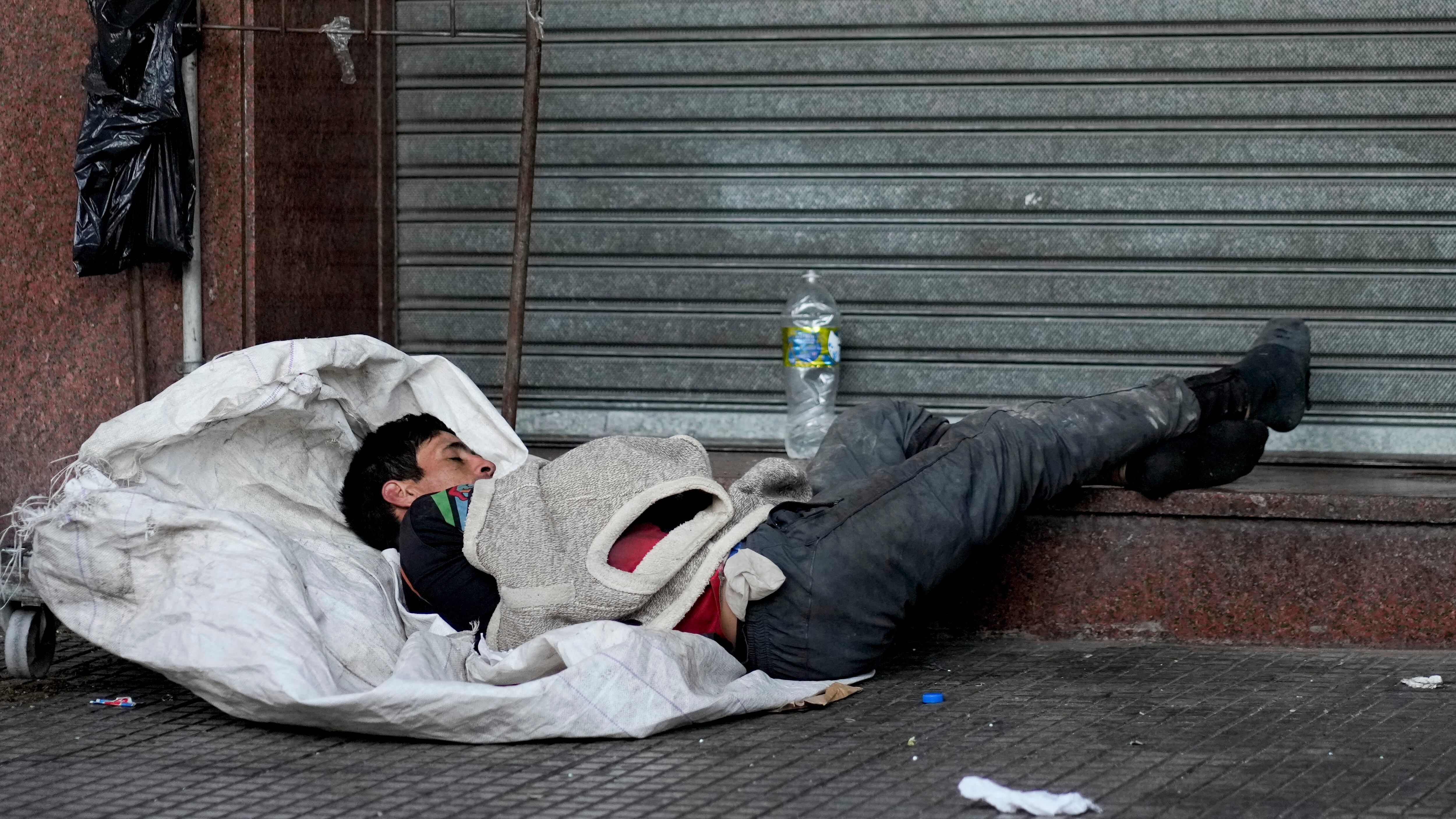 Un reciclador, que recolecta materiales para revender, duerme en su carrito en una acera en Buenos Aires (AP foto/Natacha Pisarenko)