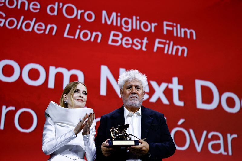 La presidenta del jurado del Festival de Venecia, Isabelle Huppert, junto a Pedro Almodóvar al recibir el premio a mejor película por "La habitación de al lado"