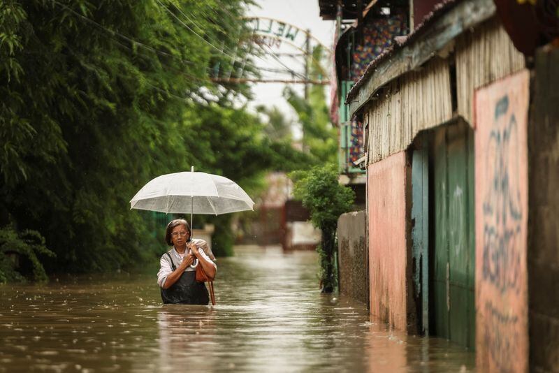 Una mujer vadea las aguas mientras llueve durante la tormenta tropical Yagi, en Filipinas (REUTERS/Eloísa López)