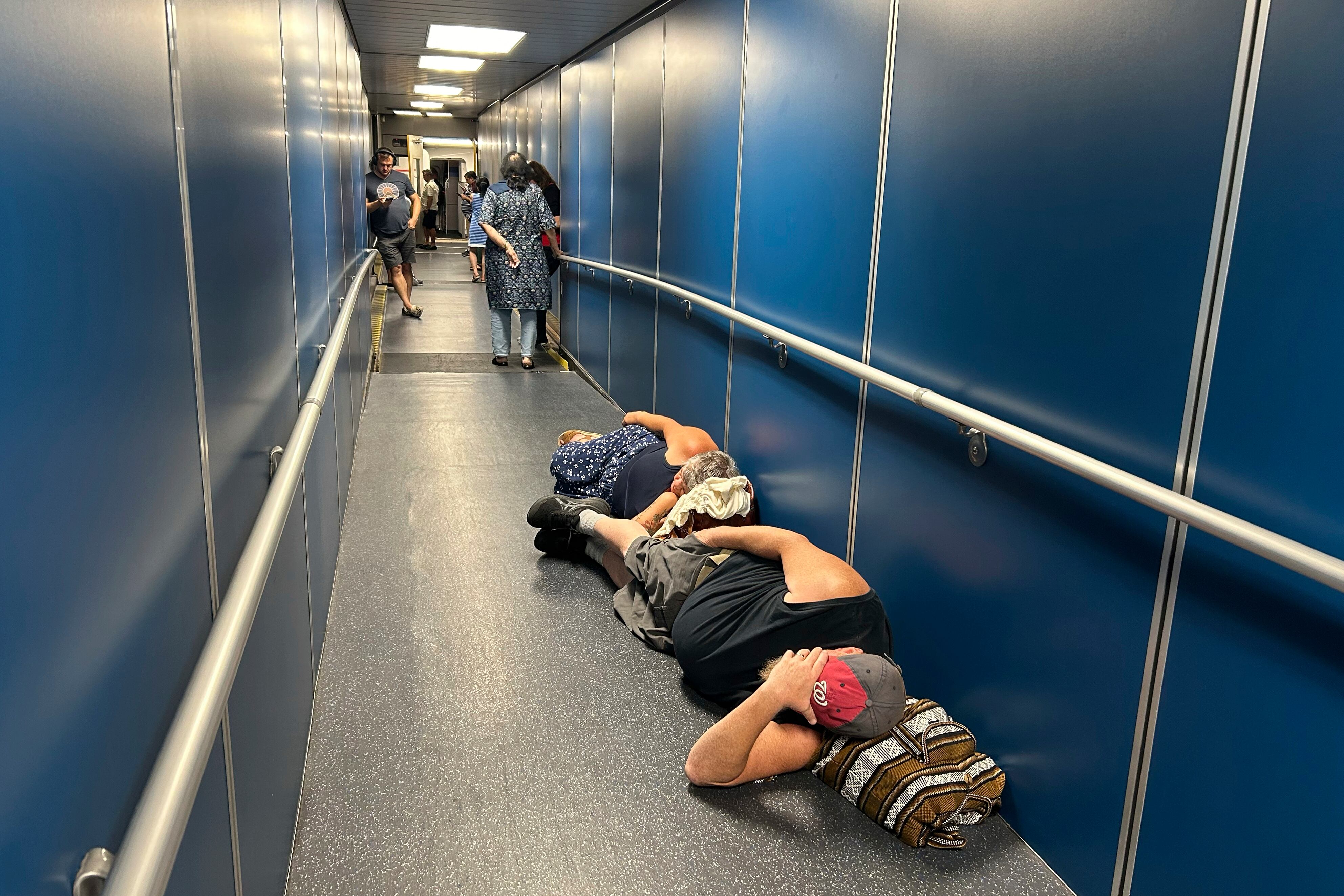 Viajeros en el Aeropuerto Internacional de Los Ángeles duermen en un pasillo por una demora en un vuelo de United Airlines debido a una caída generalizada de internet global, el 19 de julio de 2024, en Los Ángeles (AP Foto/Stefanie Dazio)