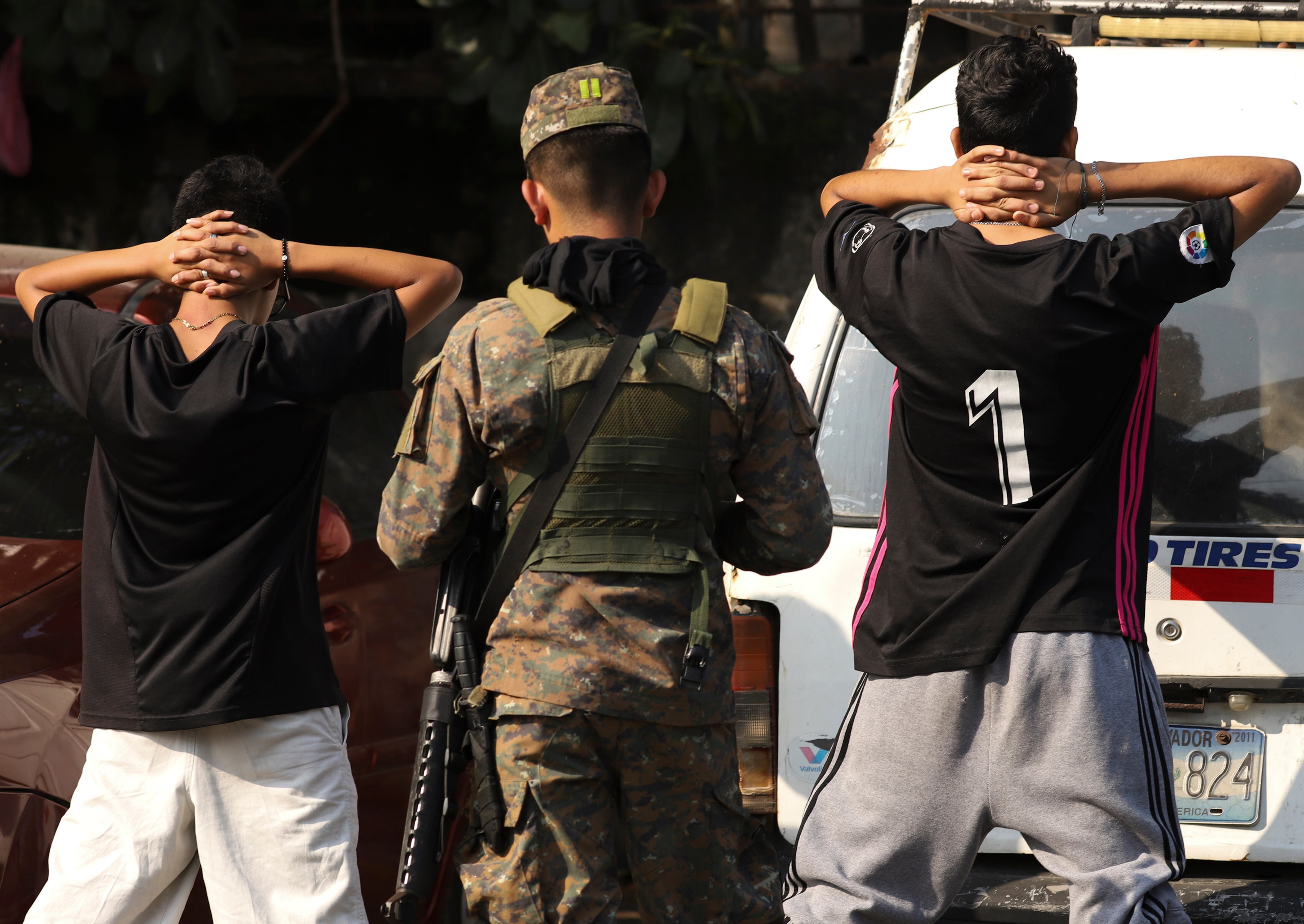 Archivo - Un soldado revisa la identificación de un grupo de jóvenes en una calle del vecindario La Campanera en Soyapango, El Salvador  (AP Foto/Salvador Meléndez, Archivo)