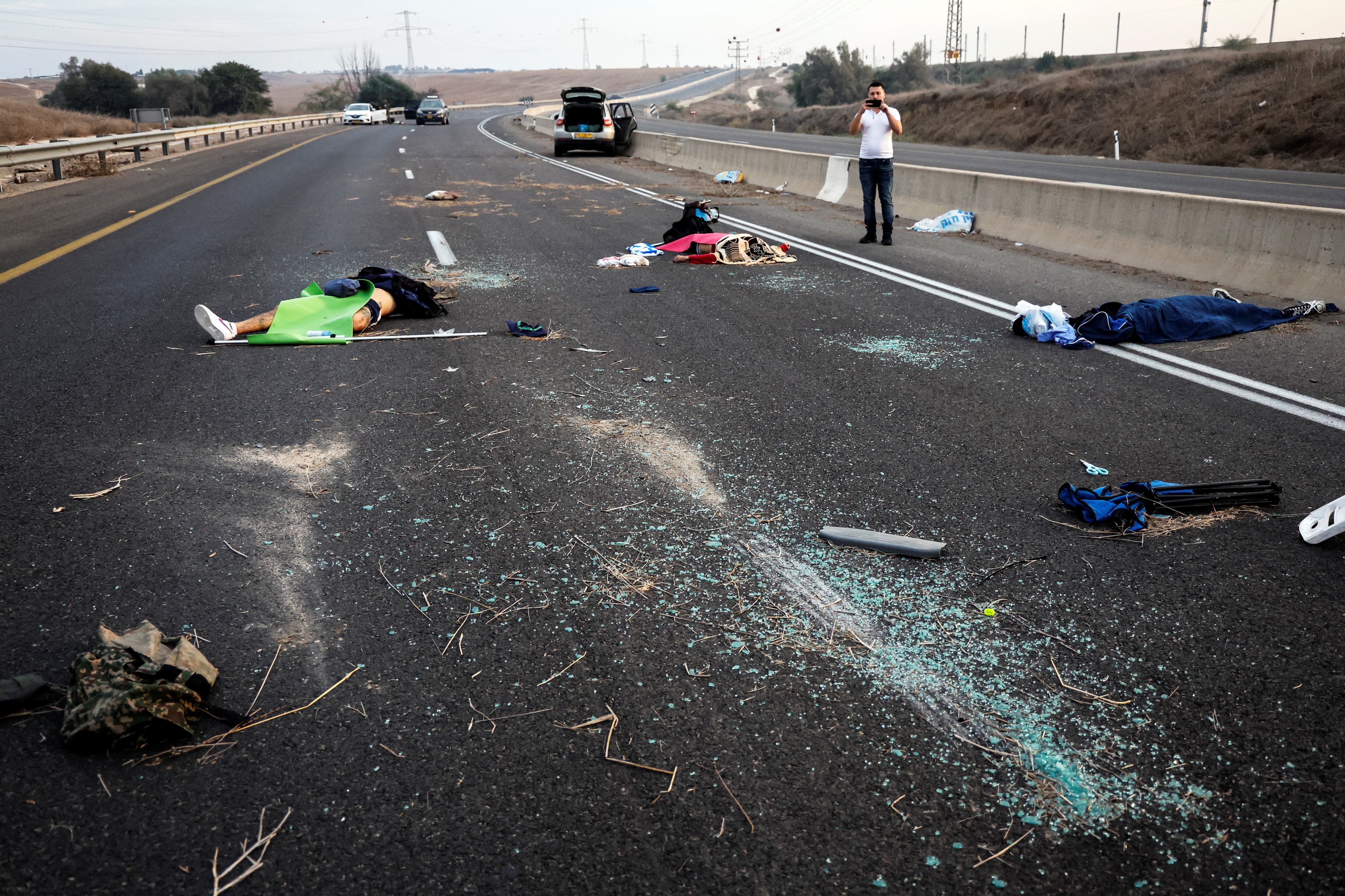 Un hombre toma una fotografía de personas muertas en una carretera en el área de Sderot, en el sur de Israel