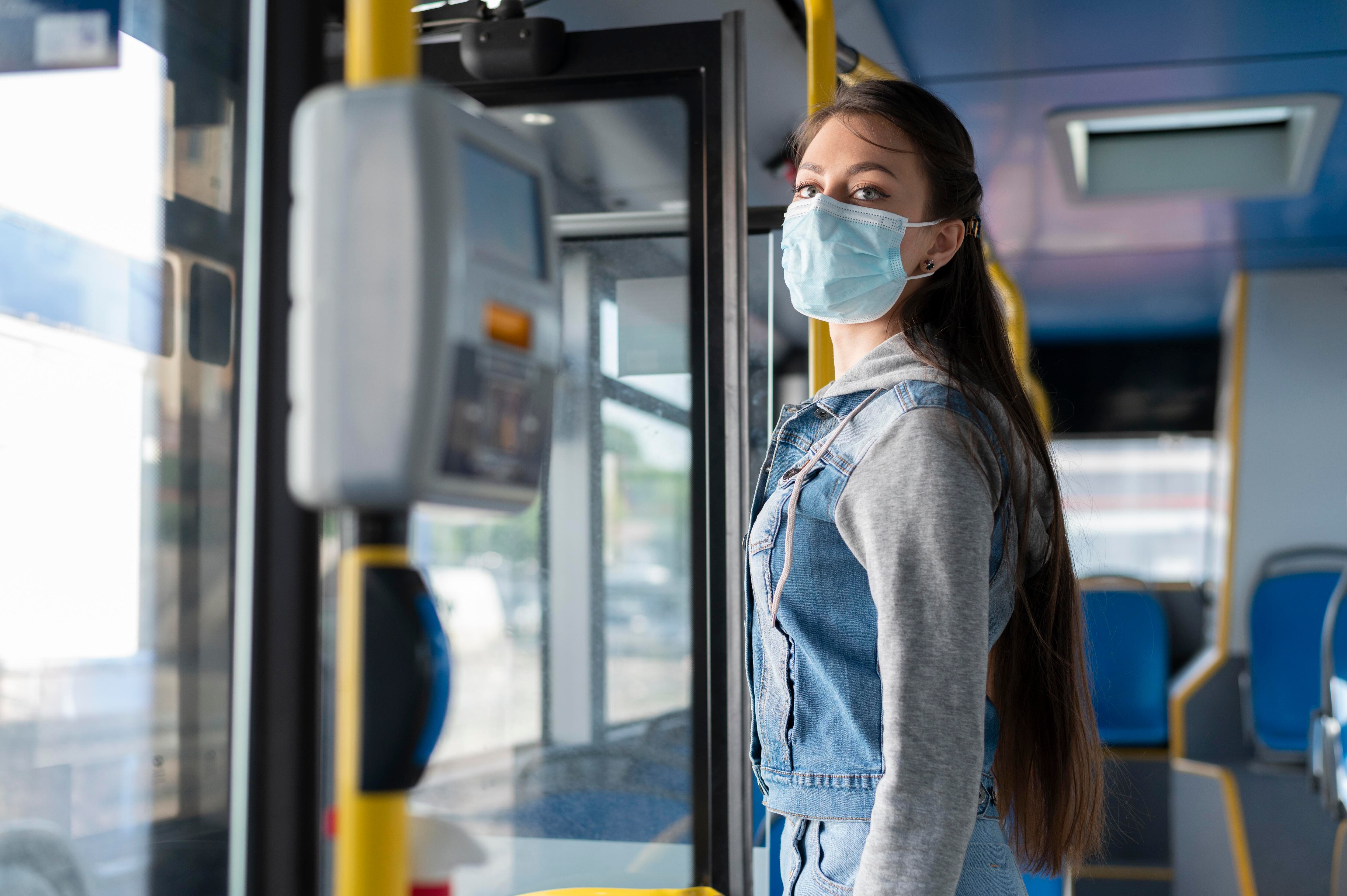 Mujer viajando en autobús con mascarilla (Freepik)