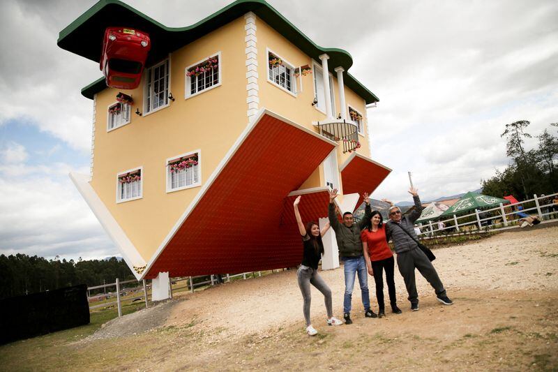 Personas posan para una foto afuera de la casa al revés, en Guatavita, Colombia, 23 de enero - crédito Luisa González/Reuters