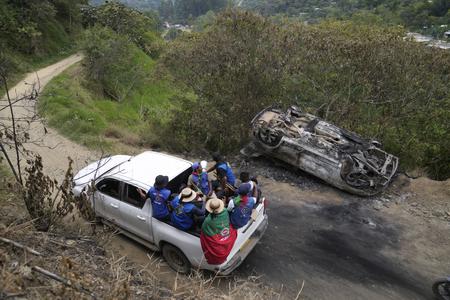 Miembros de la Guardia Indígena pasan junto a un vehículo que quemaron después de un ataque de rebeldes del Estado Mayor Central en Toribío, Colombia, el martes 19 de marzo de 2024. La líder indígena Carmelina Yule Paví fue asesinada por los rebeldes el 16 de marzo luego de que miembros de la comunidad Nasa intentaran impedir que secuestraran a un joven. (AP Foto/Fernando Vergara)