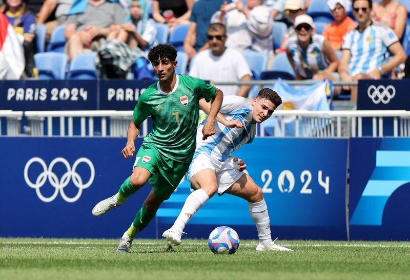 Ali Jasim, de Irak, forcejea con el argentino Julián Álvarez en el partido de fútbol entre Irak y Argentina por el Grupo B, en los Juegos Olímpicos de París 2024, en el estadio Dcines-Charpieu, de Lyon, Francia, el 27 de julio de 2024. (REUTERS/Nir Elias)