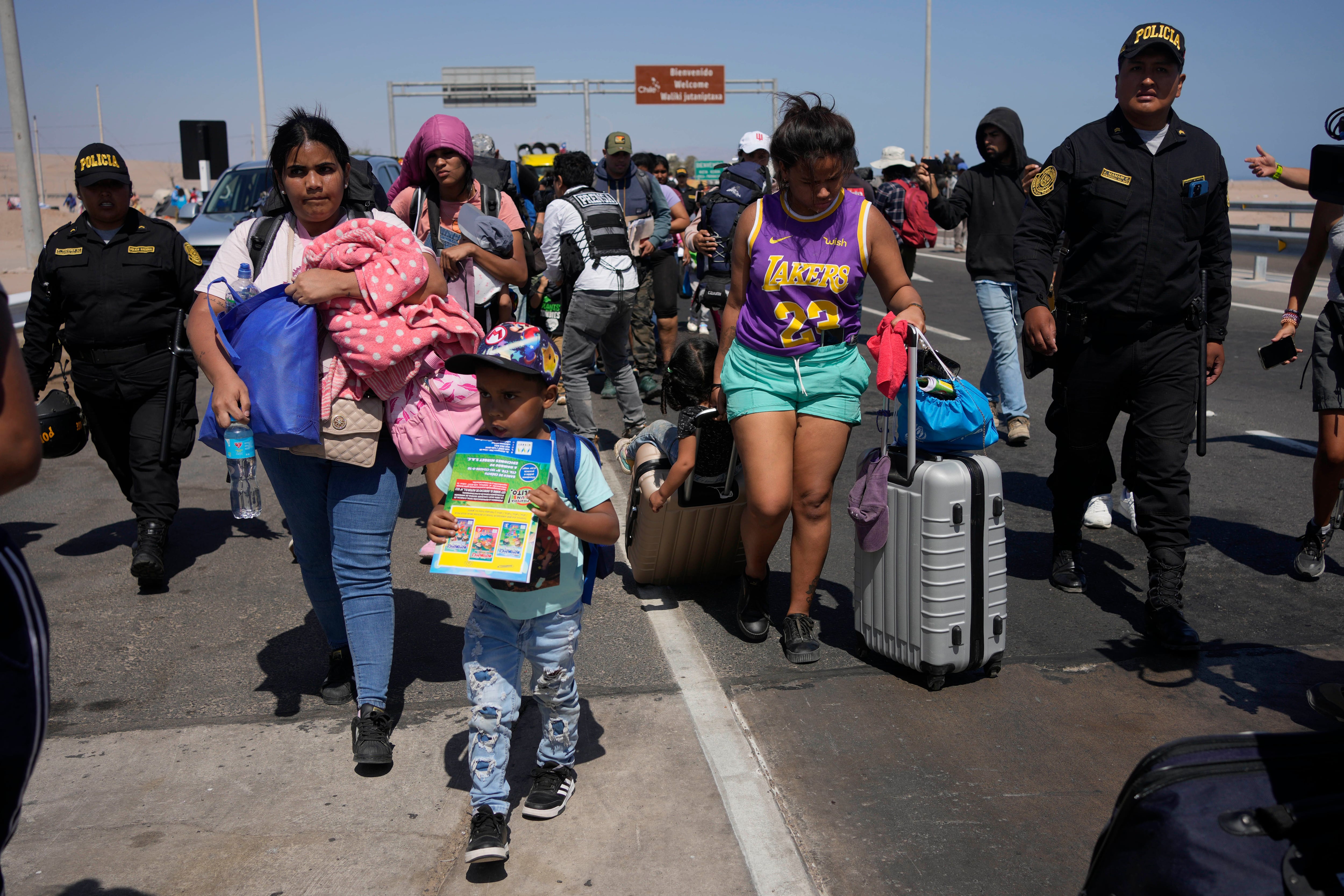 Migrantes venezolanos escoltados por la policía peruana hacia una oficina de migración en la frontera con Chile, en Tacna, Perú.