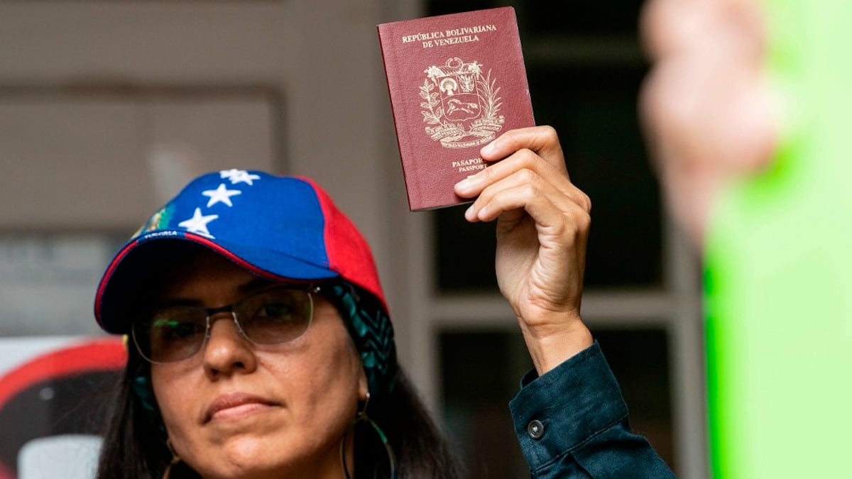 Una ciudadana venezolana, con una gorra de los colores de su país, tiene entre su mano una pasaporte.