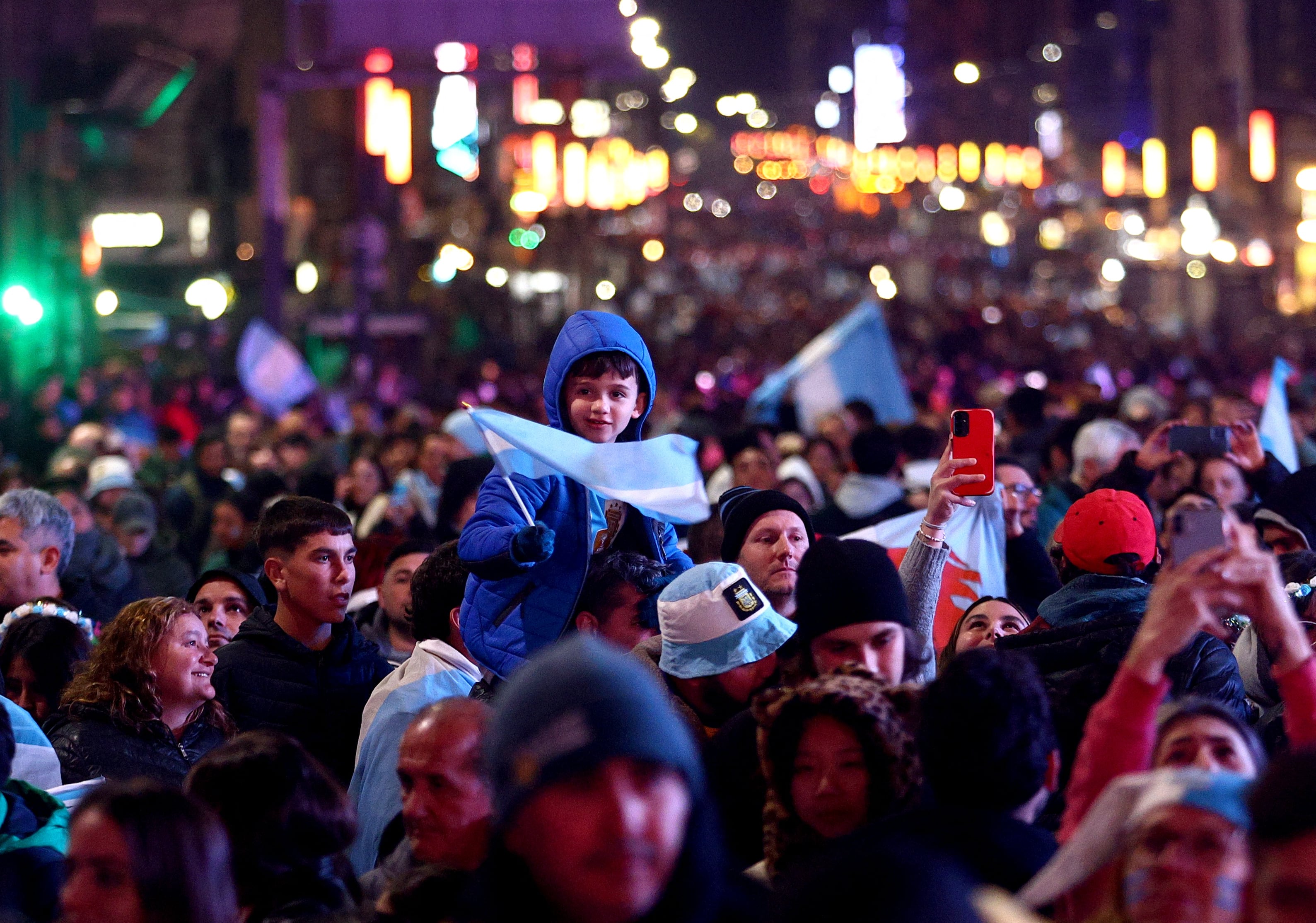 Los hinchas argentinos con banderas, bufandas y gorros caminan para festejar en el Obelisco