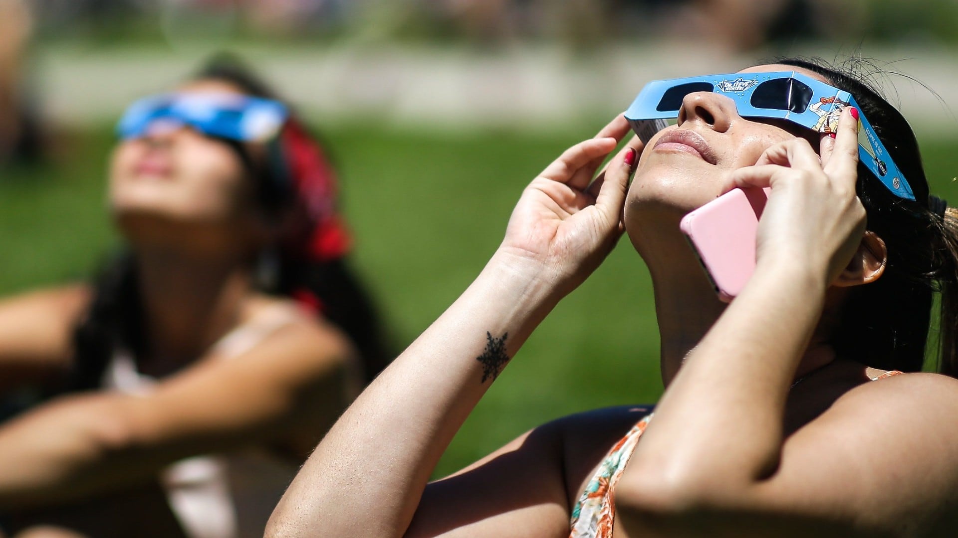 Una mujer observa el eclipse solar con lentes especiales, desde los exteriores del Planetario hoy, en Buenos Aires (Argentina). EFE/ Juan Ignacio Roncoroni