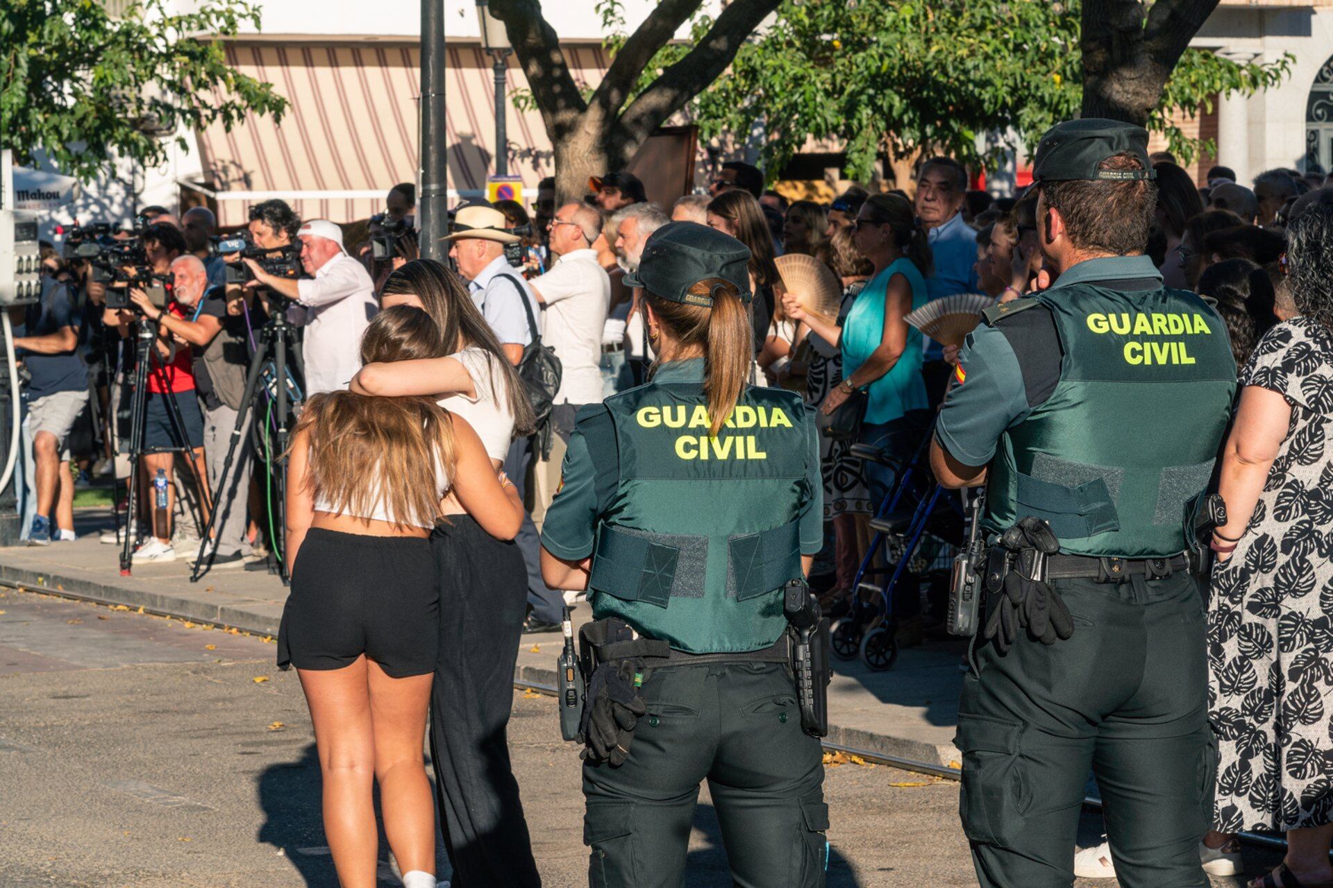 Dos agentes de la Guardia Civil observan a dos chicas abrazadas durante el minuto de silencio. (Juan Moreno./ Europa Press)
