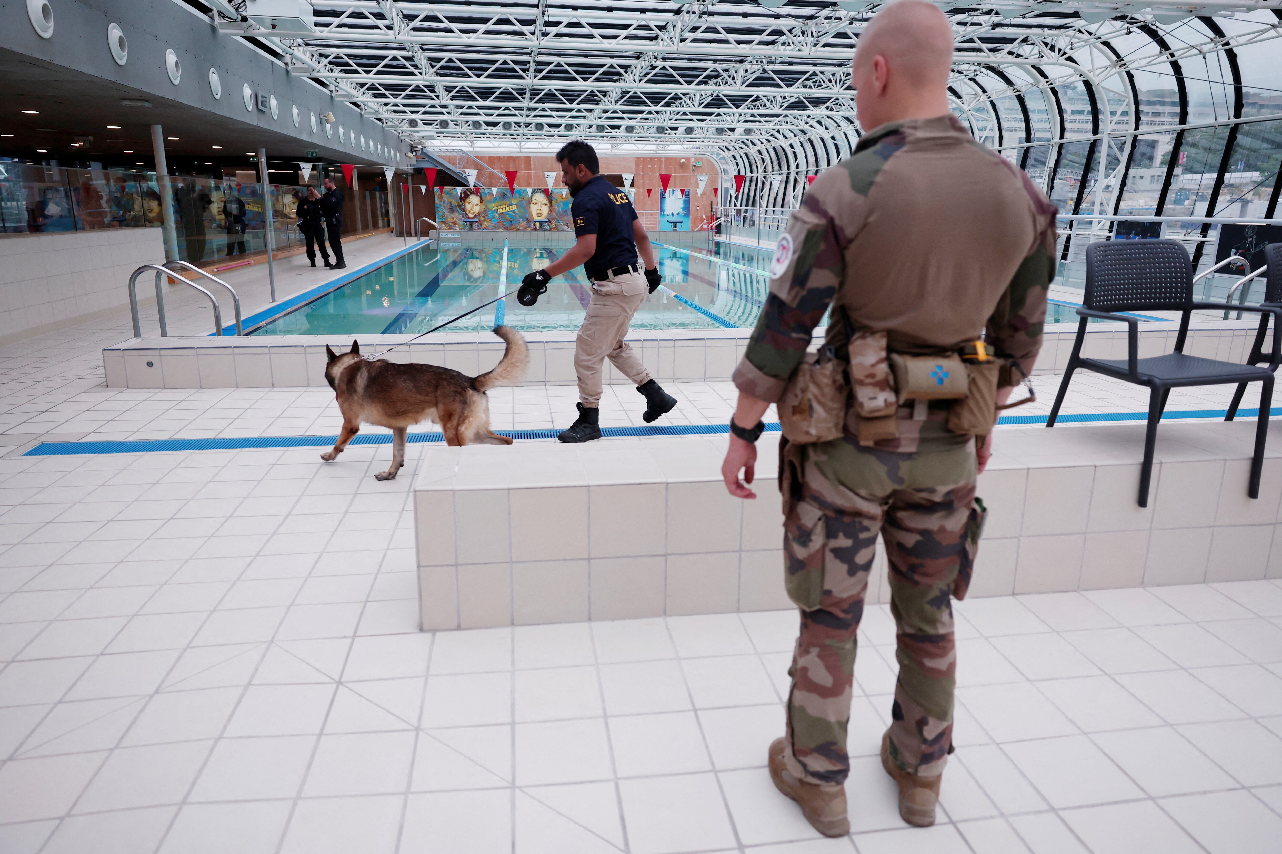 Un agente de policía y un perro rastreador inspeccionan una zona de piscinas antes de los Juegos Olímpicos (REUTERS/Gonzalo Fuentes)