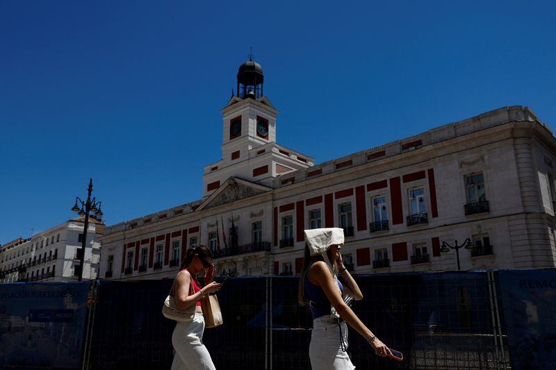 Una mujer se cubre la cabeza con una bolsa mientras camina por Puerta del Sol durante un día de calor en Madrid. (REUTERS/Susana Vera)