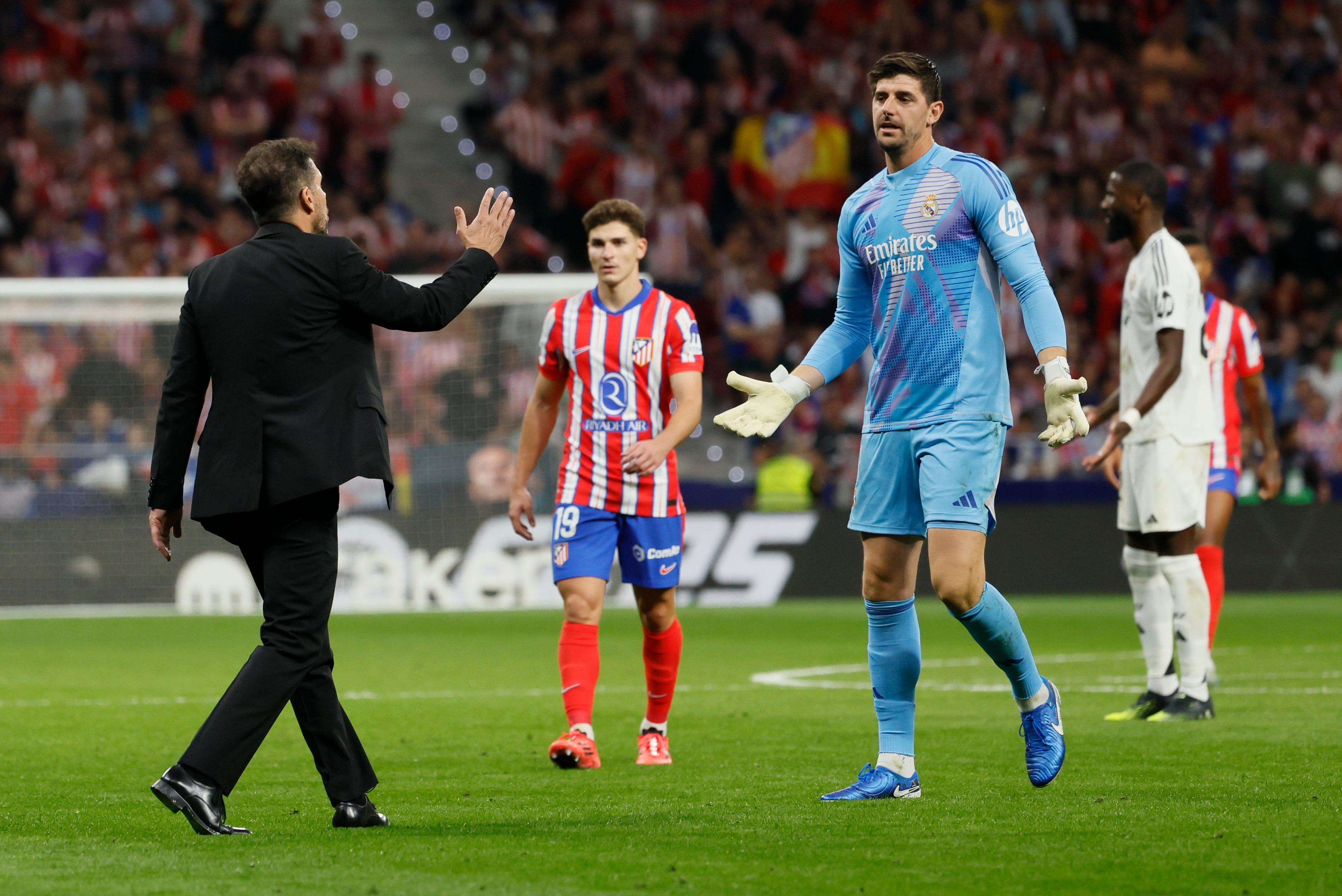 El portero del Real Madrid Thibaut Courtois (d) conversa con el entrenador del Atlético, Diego Simeone (i) (EFE/Ballesteros)
