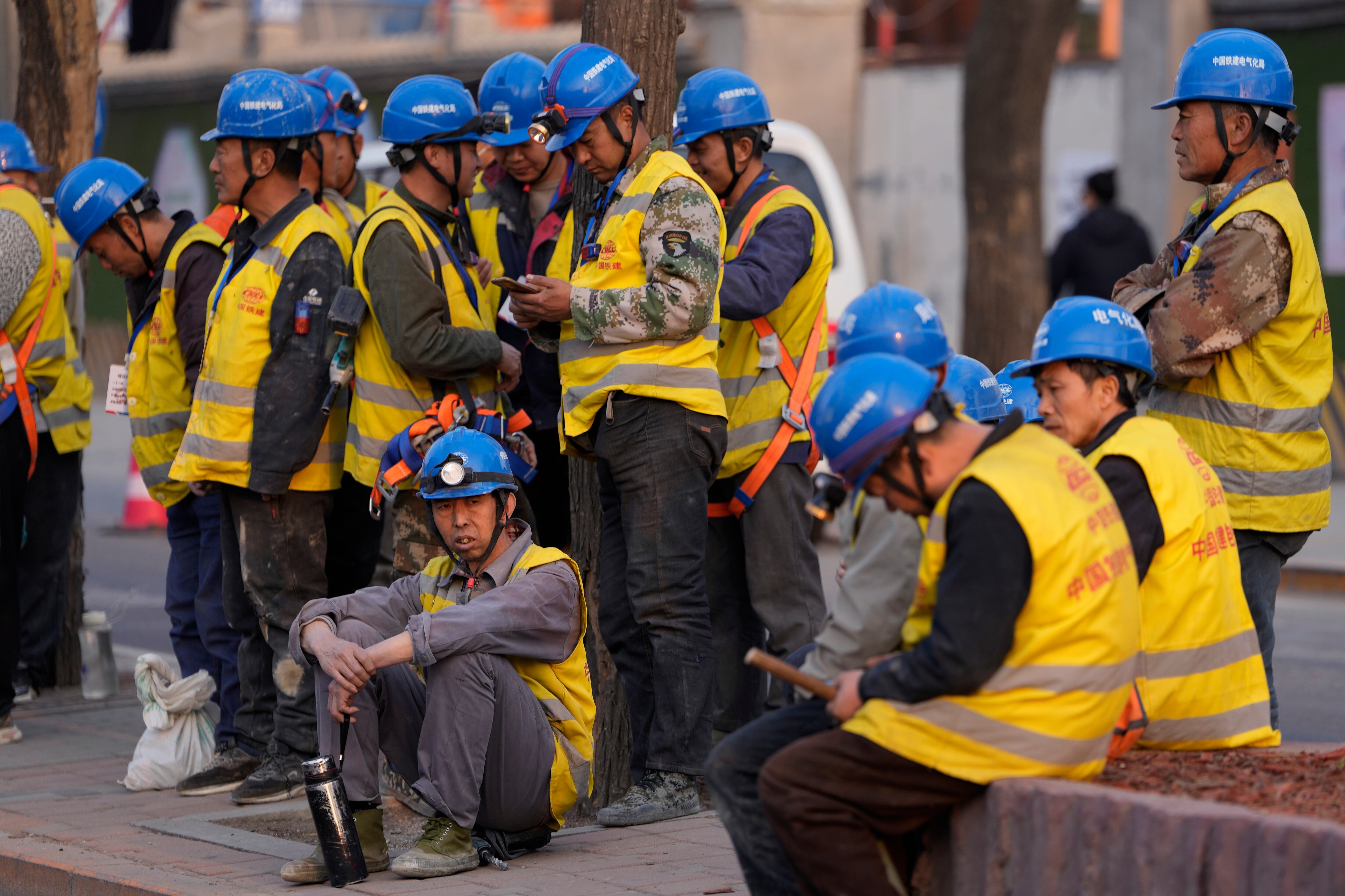 Trabajadores esperan transporte afuera de una obra en Beijing.(AP Foto/Ng Han Guan)