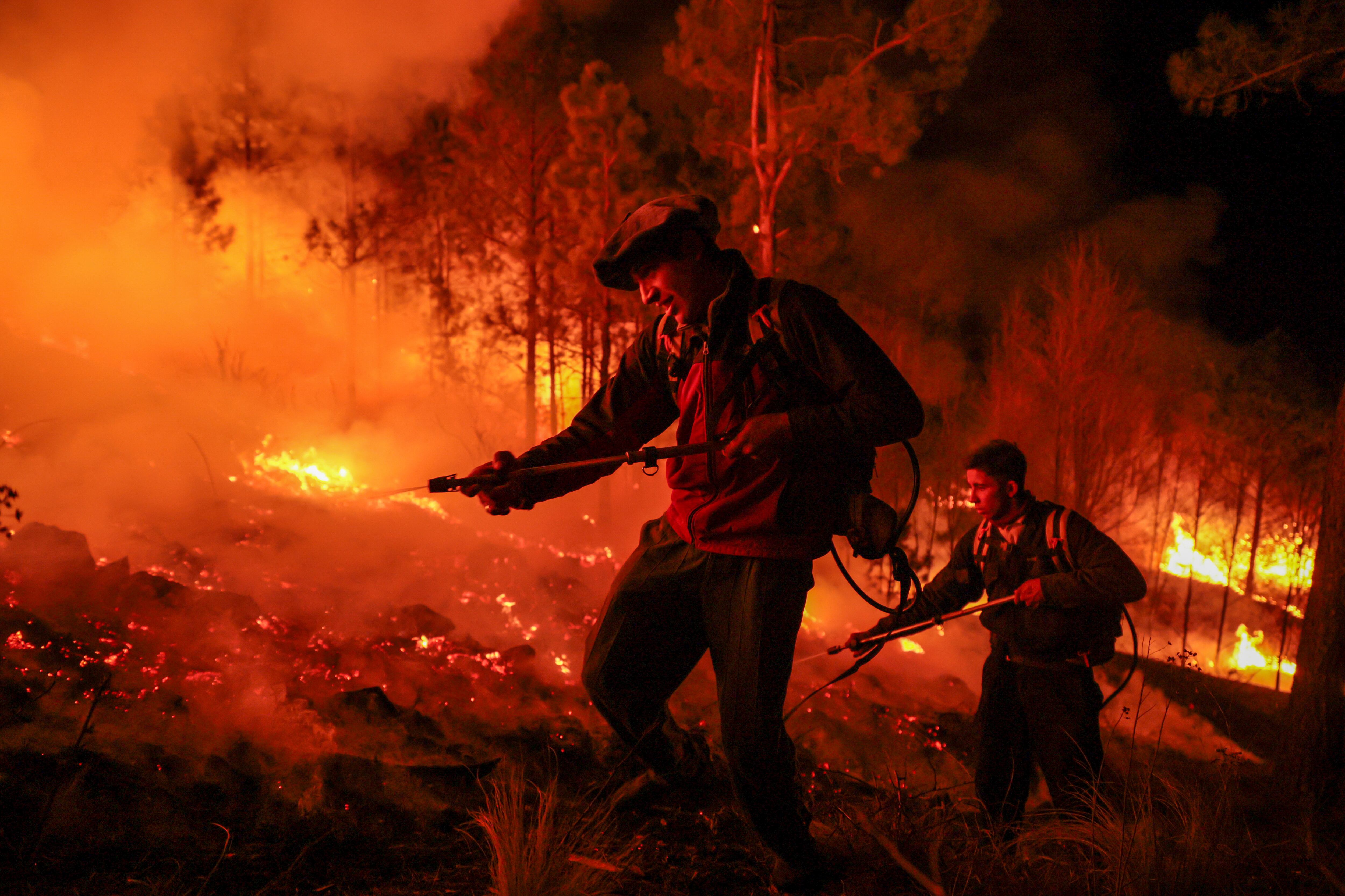 Dos hombres parte de un grupo de bomberos y vecinos autogestionados combaten un incendio forestal este lunes, en Intiyaco en las cercanías de Villa Berna, provincia de Córdoba (Argentina). EFE/ STR
