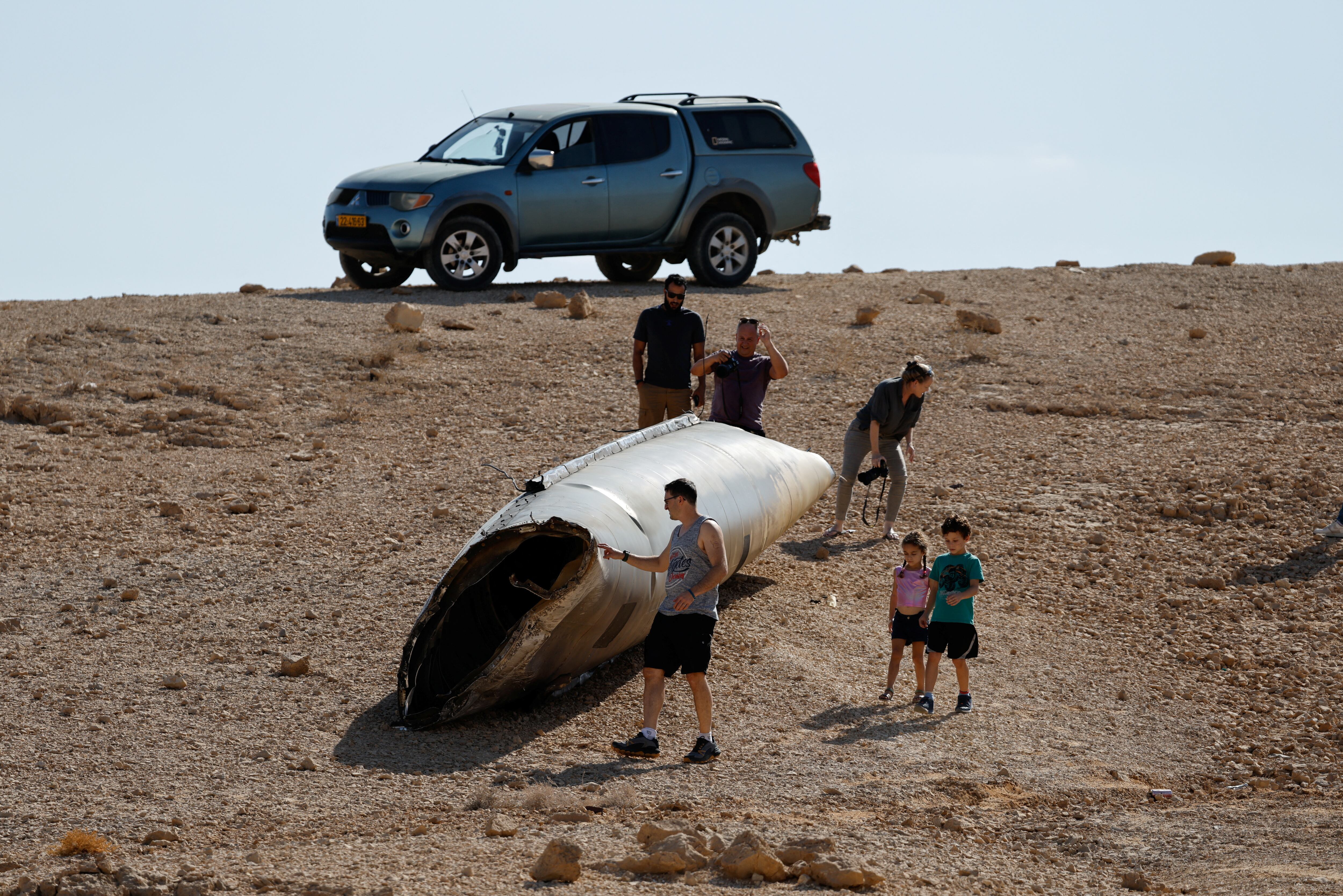 Personas caminan alrededor de los restos de un misil en Arad, Israel 