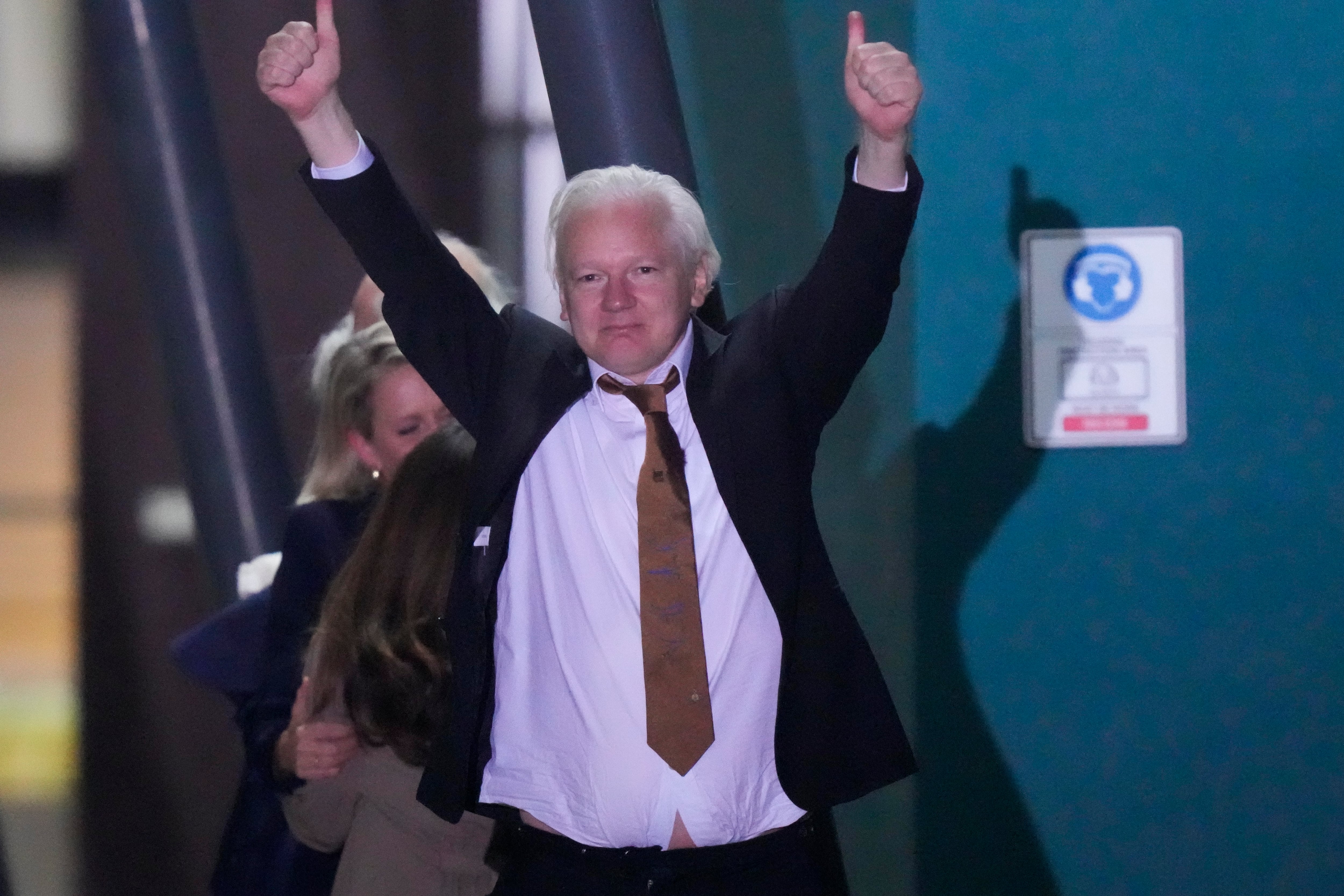 Julian Assange, fundador de WikiLeaks, hace un gesto con los brazos y los pulgares en alto tras aterrizar en la base de las Fuerzas Armadas Australianas en Fairbairn, Canberra, Australia, el 26 de junio de 2024. (AP Foto/Rick Rycroft)