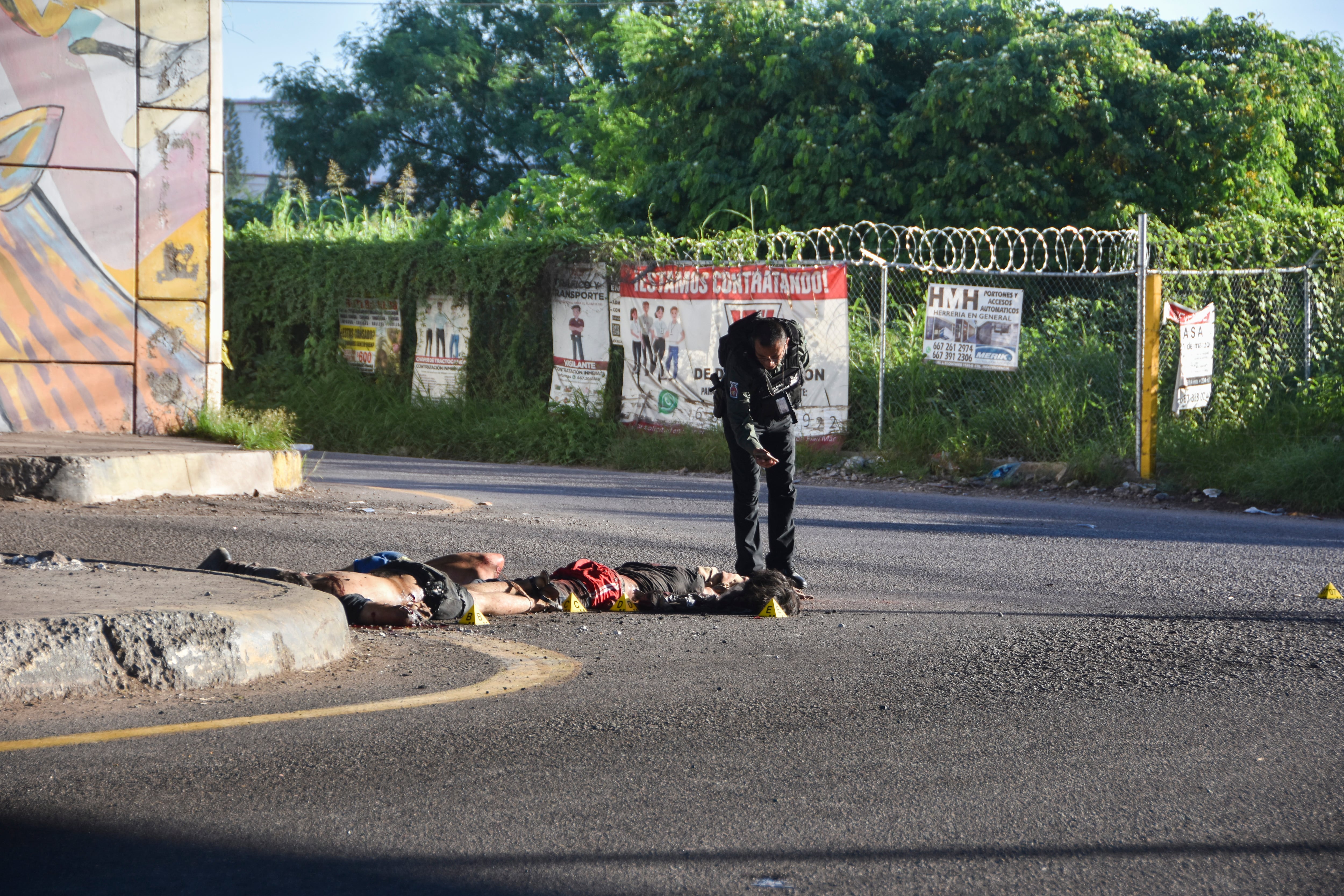 Un oficial de policía toma una fotografía de la escena del crimen en donde se ve cuerpos sobre el piso en Culiacán, estado de Sinaloa, México, el miércoles 18 de septiembre de 2024. (AP Foto)