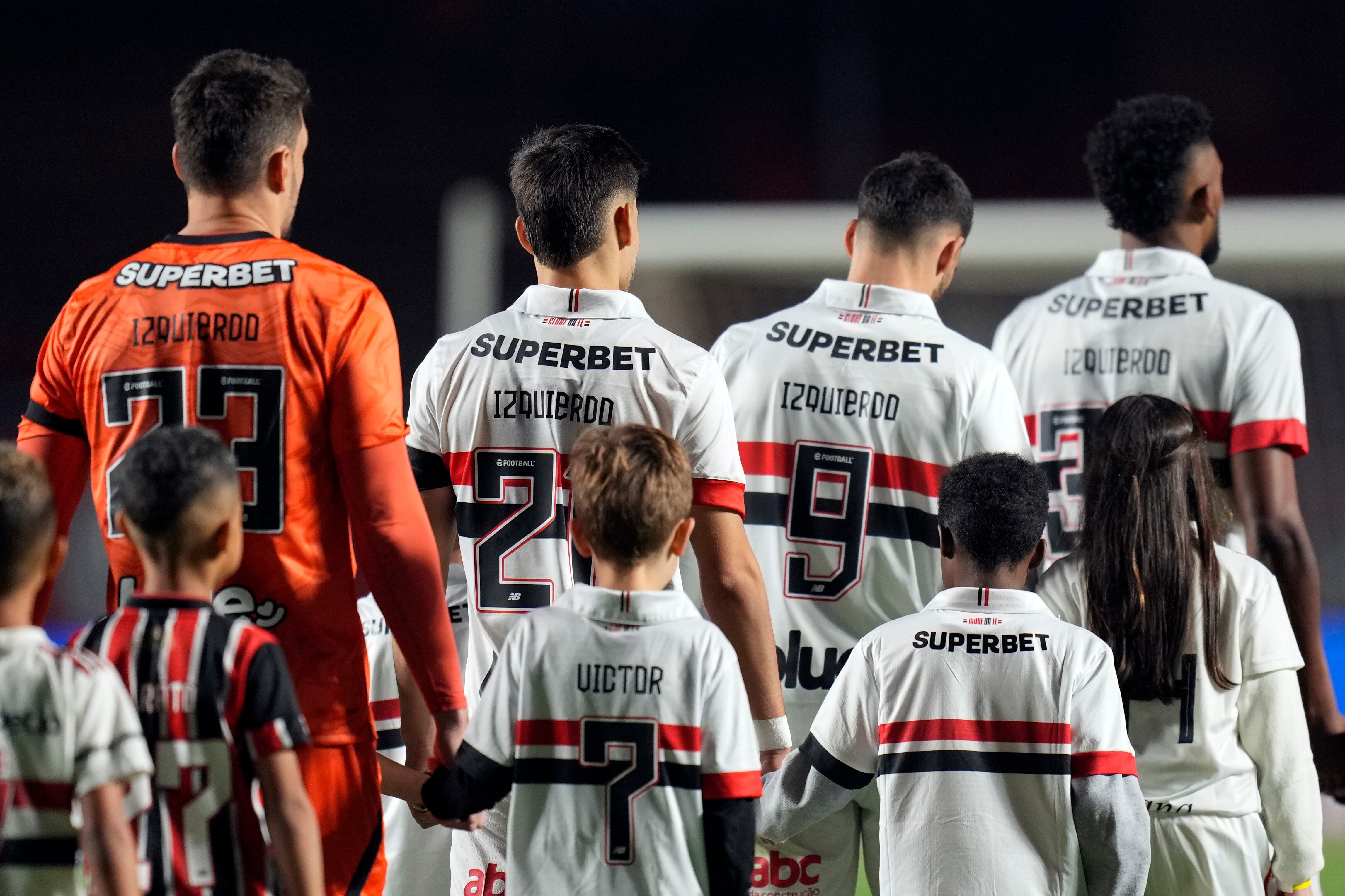 Jugadores del Sao Paulo de Brasil ingresan en la cancha portando camisetas con el apellido de Juan Izquierdo, jugador uruguayo de Nacional fallecido tras colapsar en un partido de la semana anterior. El homenaje se realizó el miércoles 28 de agosto de 2024, antes de un encuentro de la Copa de Brasil, ante Atlético Mineiro (AP Foto/Andre Penner)