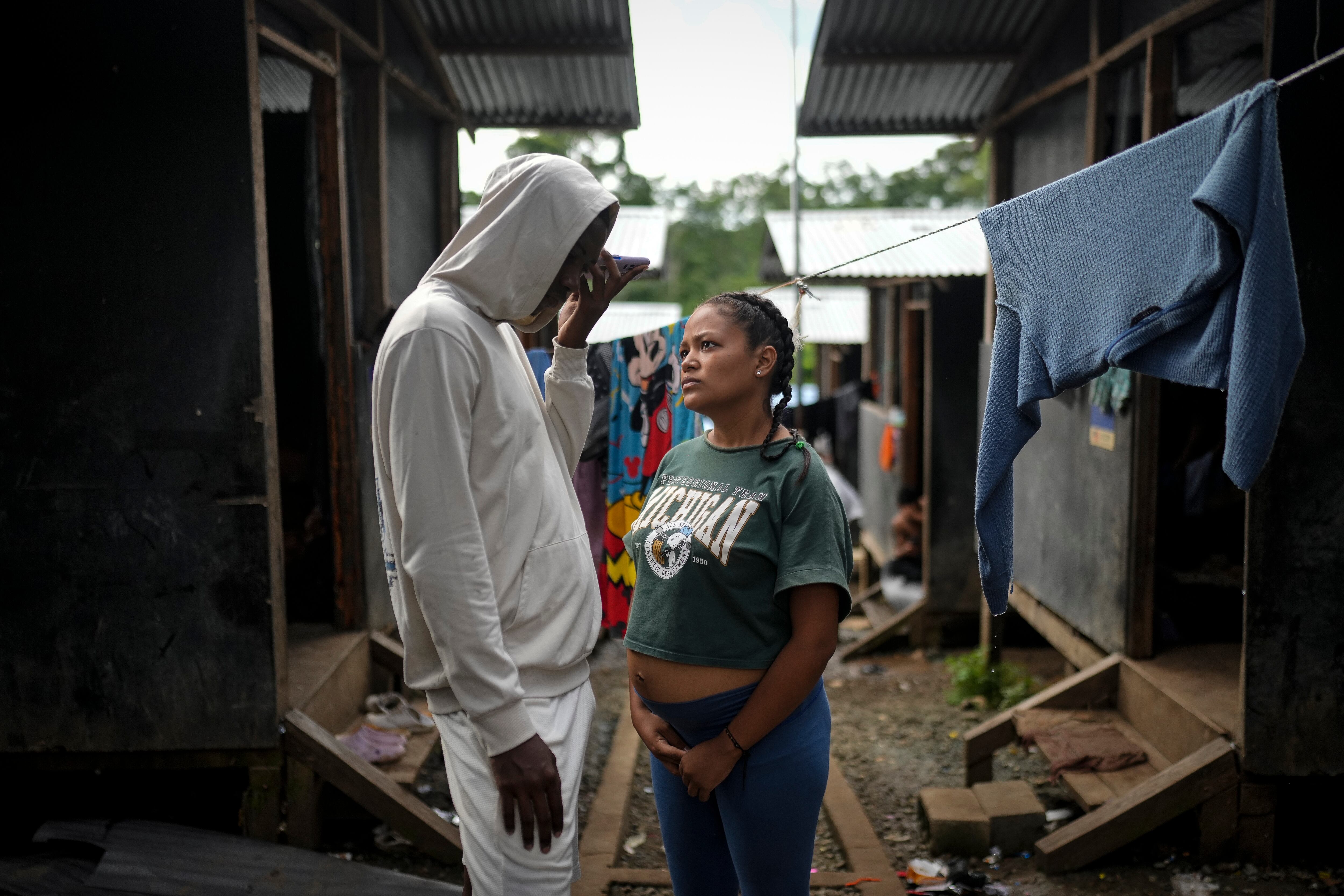La migrante colombiana Georyeth Barreto, embarazada de seis meses, junto a su prometido Anthony Herrera mientras habla por teléfono en un campamento temporal después de haber cruzado el Tapón del Darién  (Foto AP/Matías Delacroix)