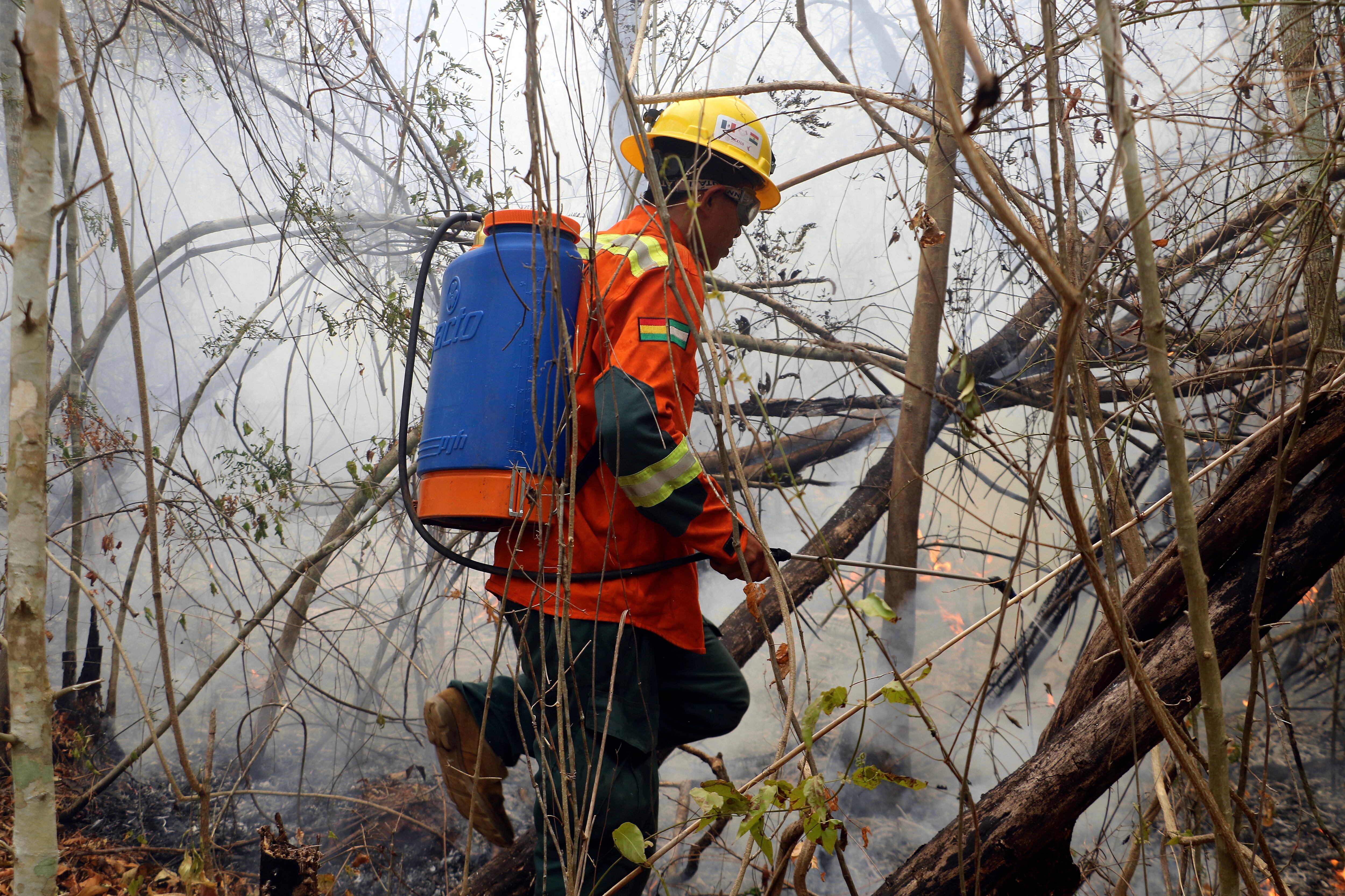 Un bombero mitiga los restos de un incendio en San Miguelito, Bolivia (EFE/Juan Carlos Torrejón)