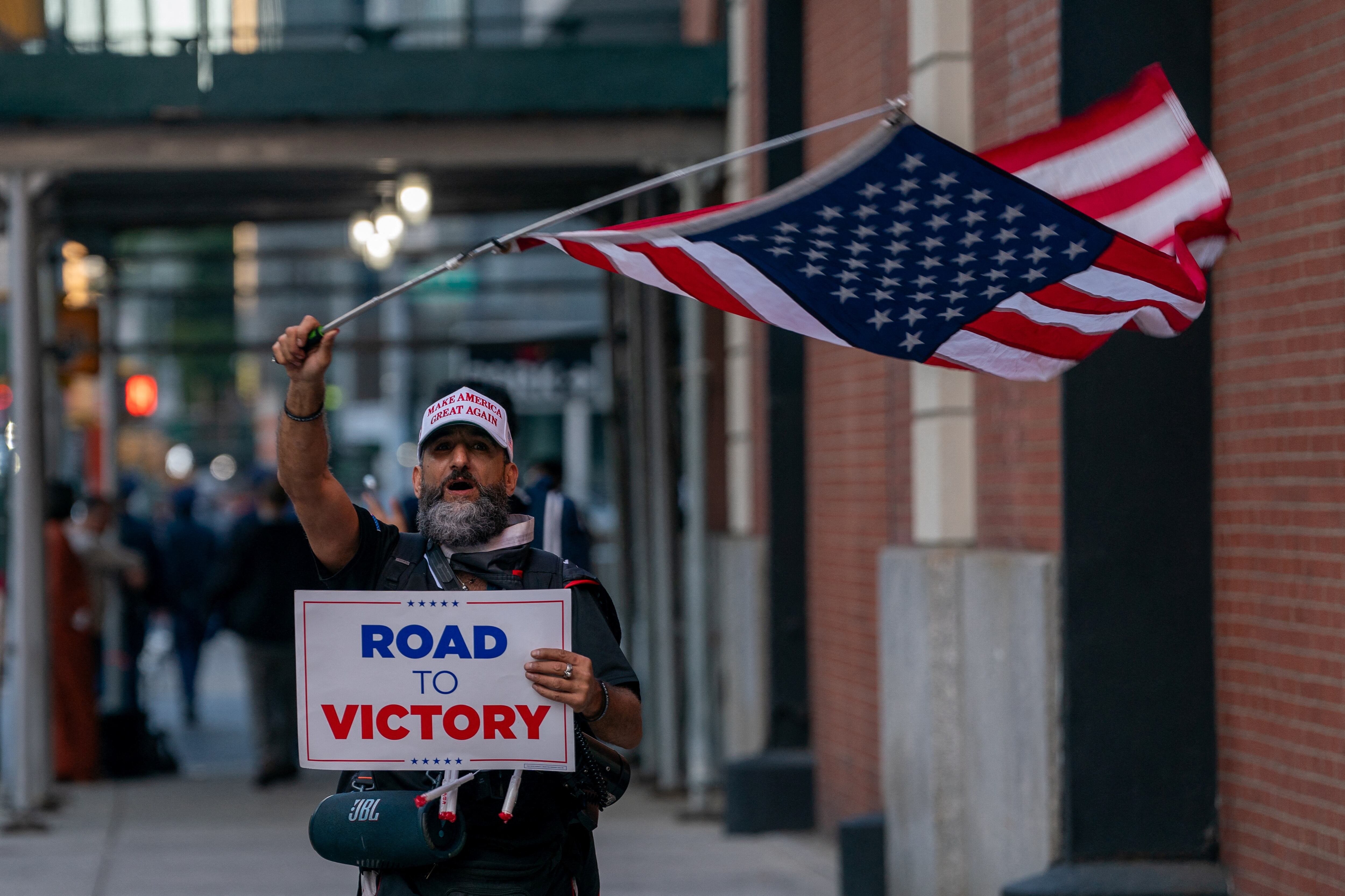 Una persona que lleva una gorra de béisbol de Make America Great Again ondea una bandera estadounidense frente al Centro de Transmisiones de CBS antes del debate (REUTERS/David Dee Delgado)