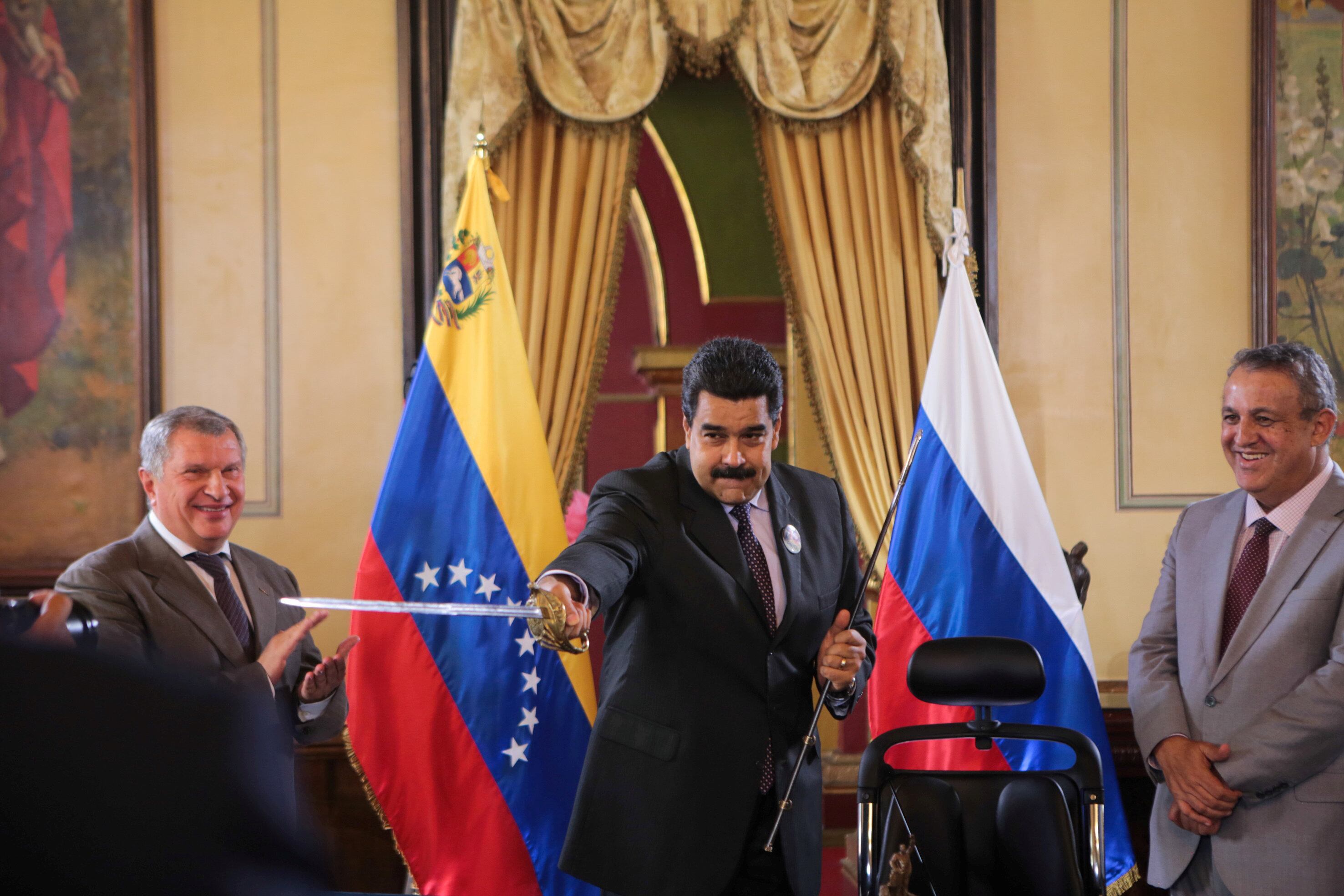 Nicolás Maduro sostiene una réplica de la espada del libertador Simón Bolívar junto al jefe del grupo petrolero ruso Rosneft, Igor Sechin, durante un acuerdo entre Rosneft y la petrolera estatal venezolana PDVSA en Caracas el 28 de julio de 2016 (REUTERS)