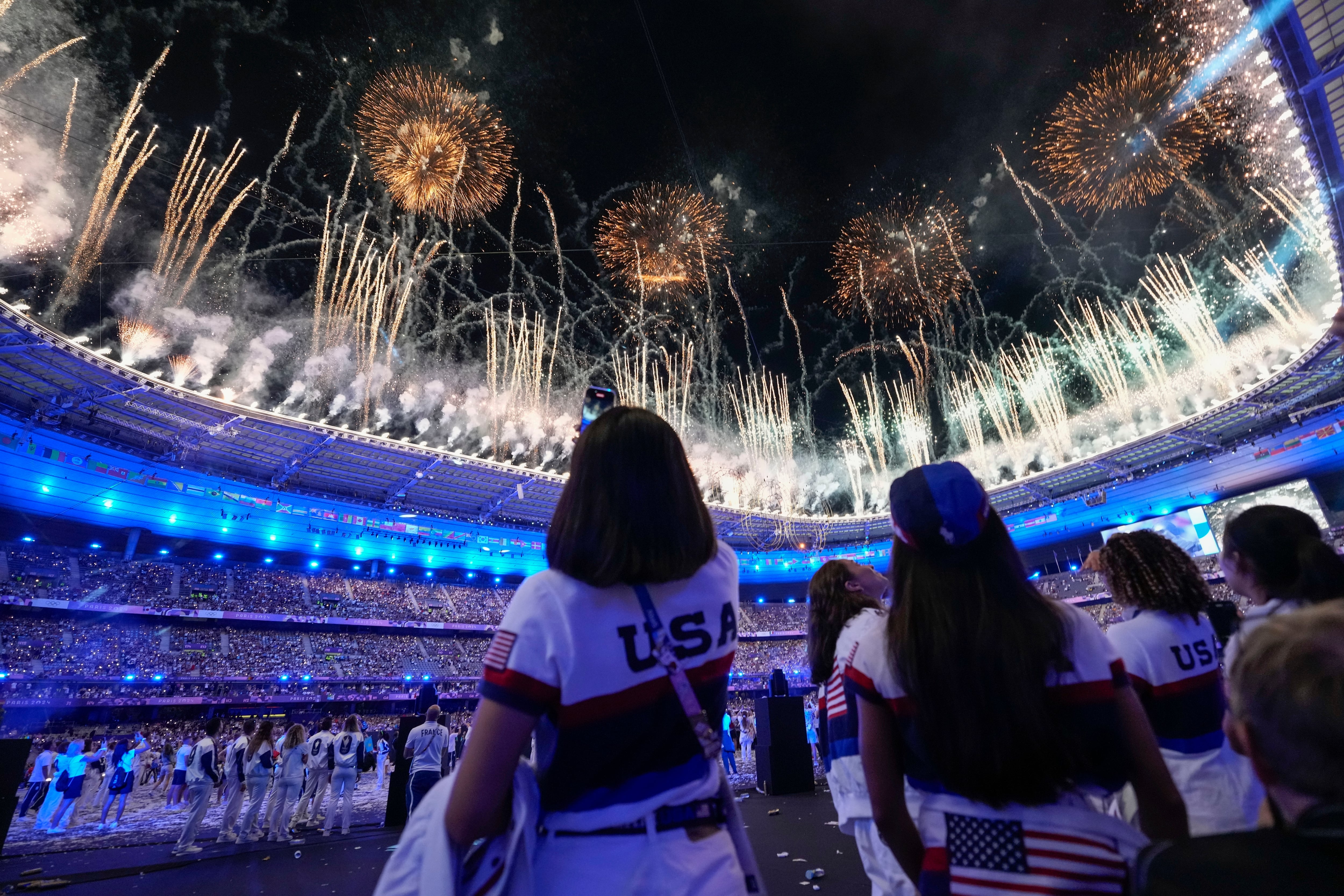 Atletas estadounidenses observan la explosión de fuegos artificiales durante la ceremonia de clausura de los Juegos Olímpicos de Verano de 2024 en el Stade de France, el lunes 12 de agosto de 2024, en Saint-Denis, Francia. (Foto AP/Ashley Landis)