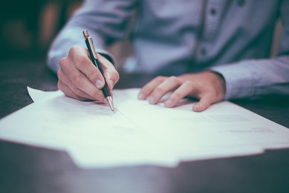 Hombre firmando un documento. Foto: Pixabay