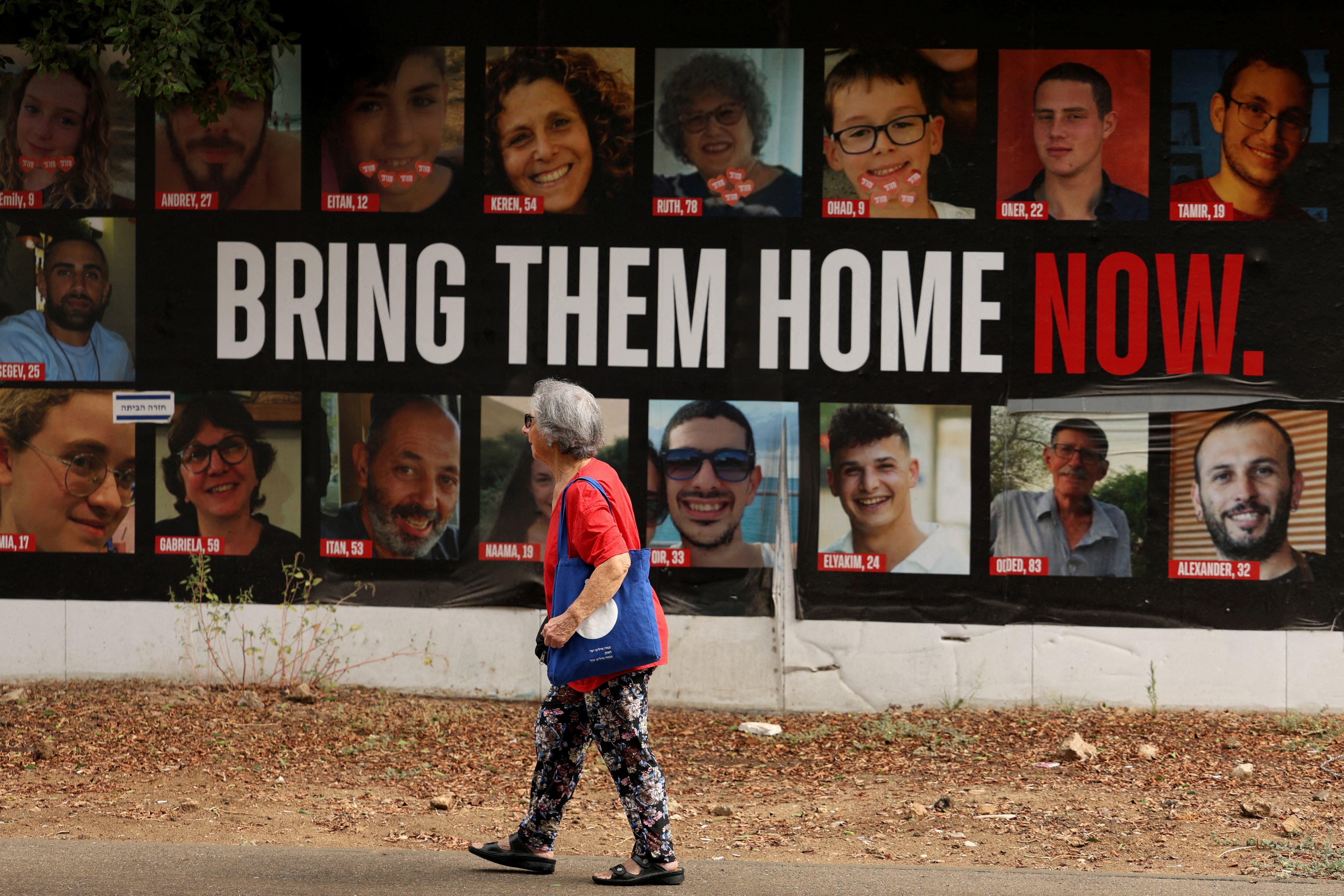 Una mujer camina junto a un cartel de los rehenes secuestrados en Tel Aviv (REUTERS/Florion Goga)