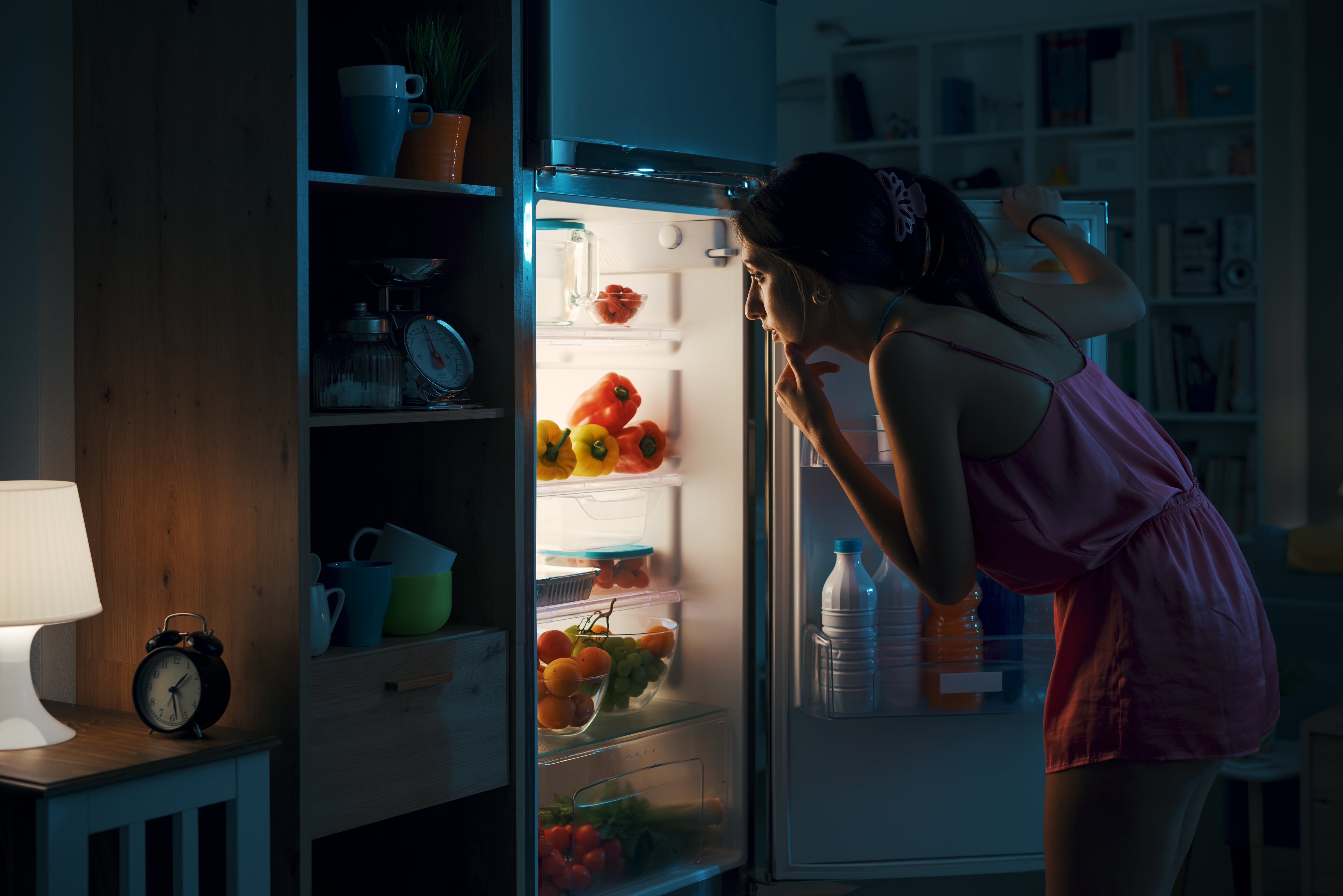 Una mujer abre el frigorífico a deshoras (Shutterstock España)