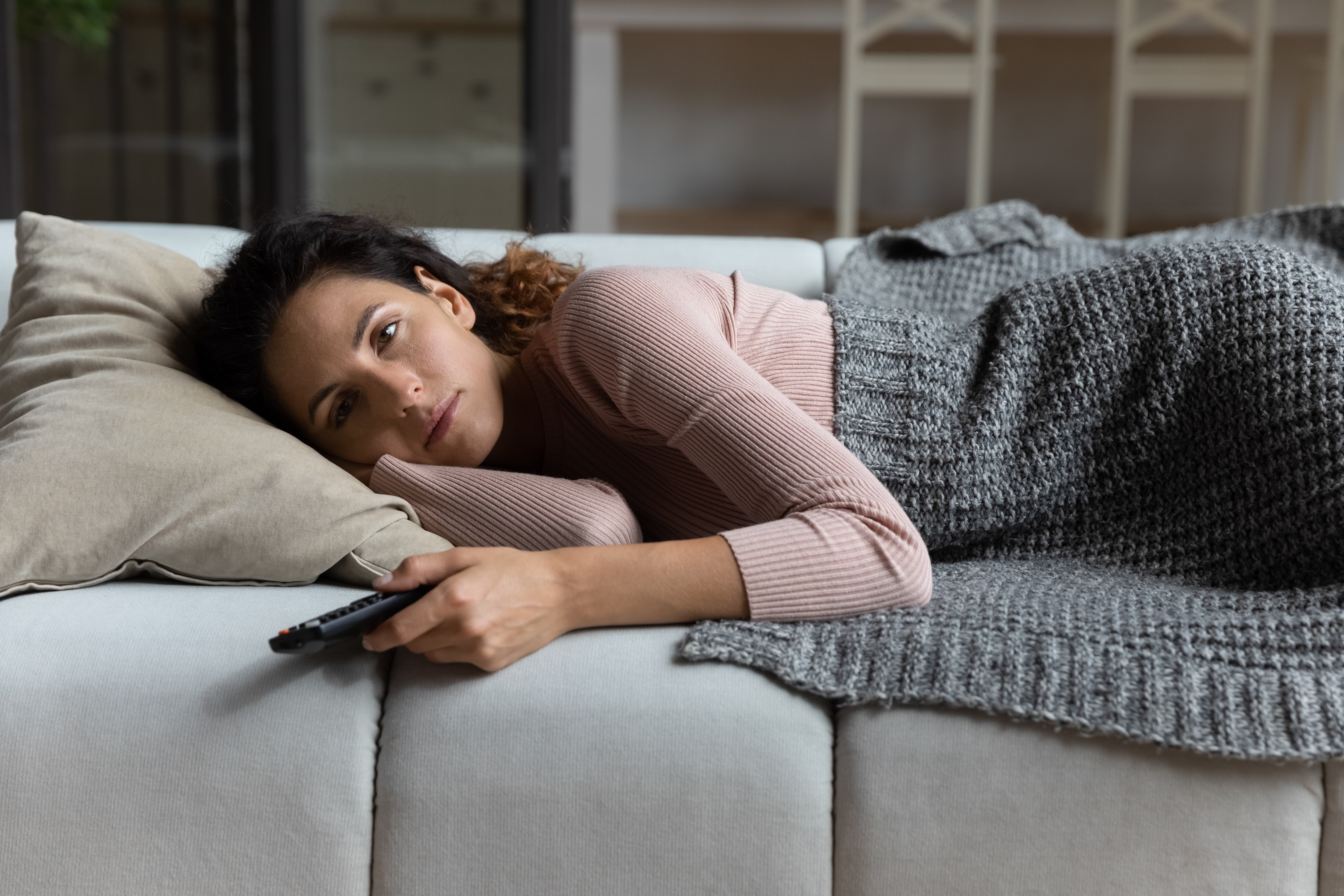 Una mujer mirando la televisión desde el sofá de su casa (Shutterstock España)